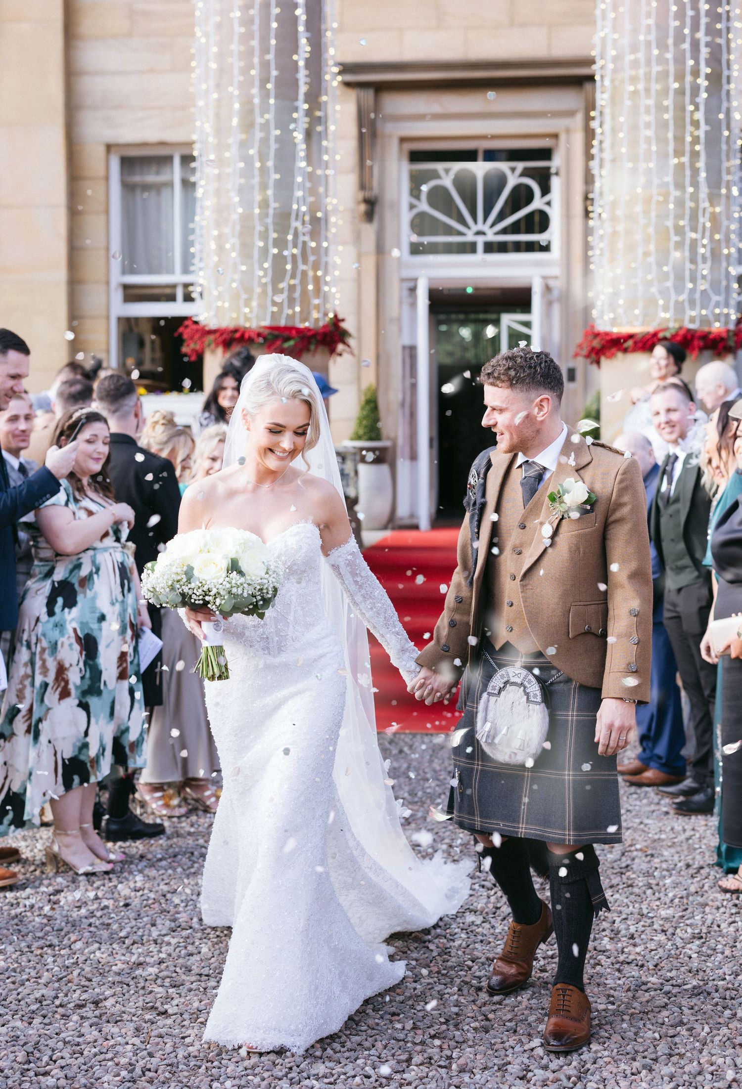 Wedding guests toss bubbles at the bride and groom as they exit celebrations at an elegant estate venue.