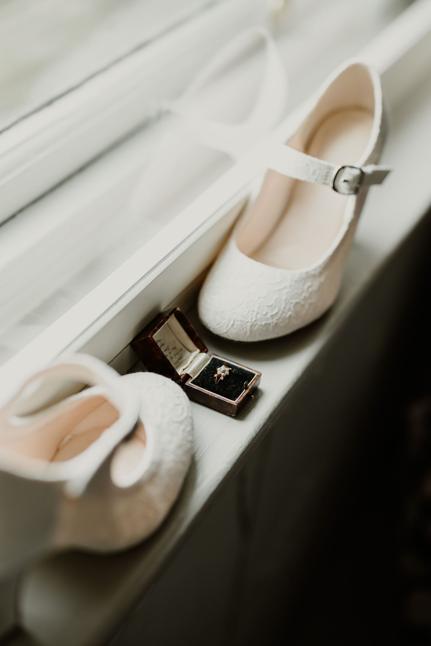 White lace bridal flats displayed with wedding rings in an elegant detail shot.