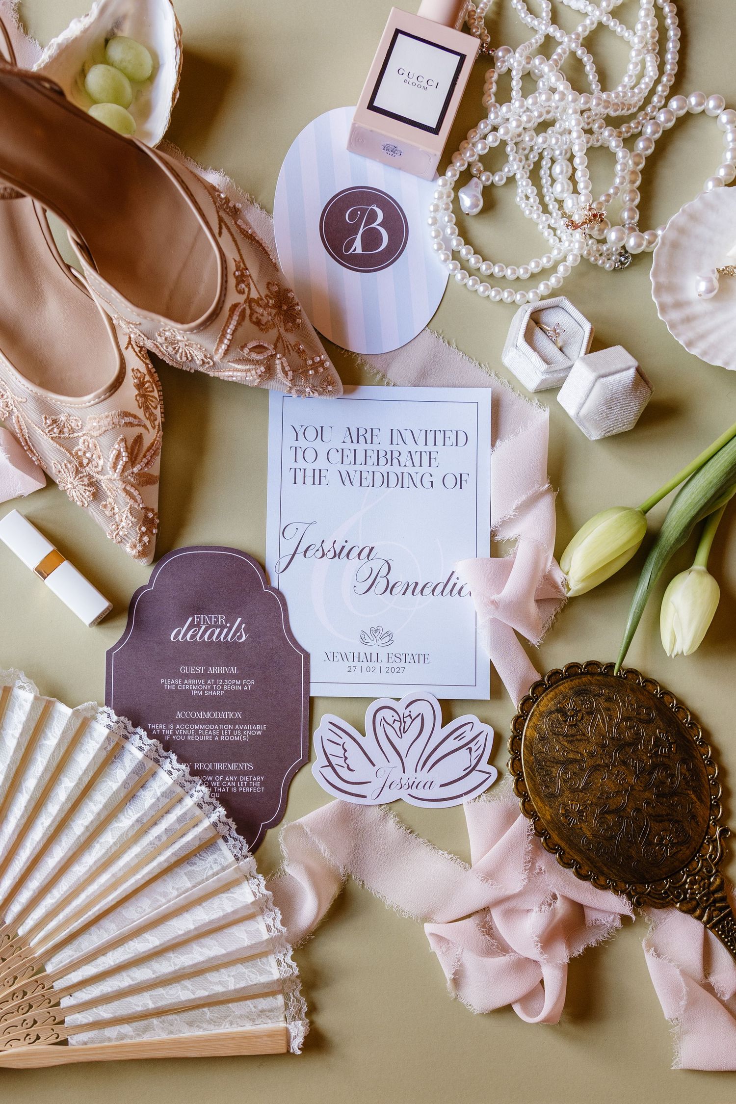 Wedding invitation suite with blush pink fans, pearl details, and floral accents on cream background.