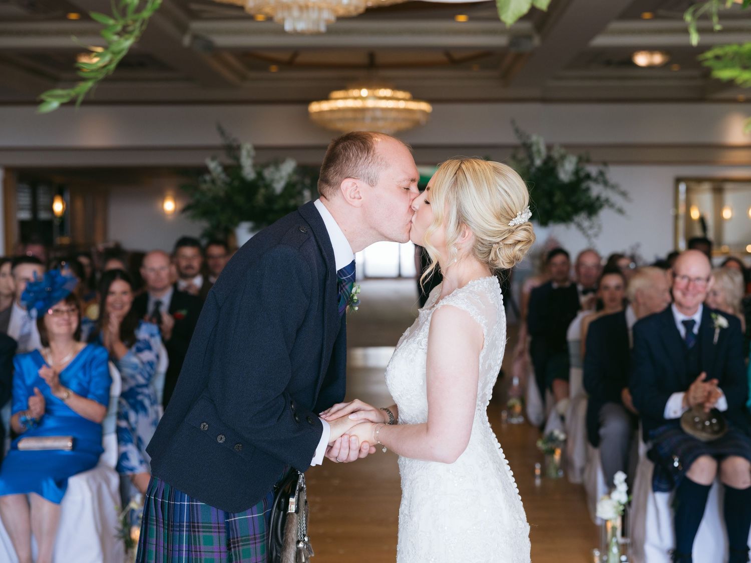 A bride and groom sharing their first dance together at an elegant wedding reception hall with guests watching.