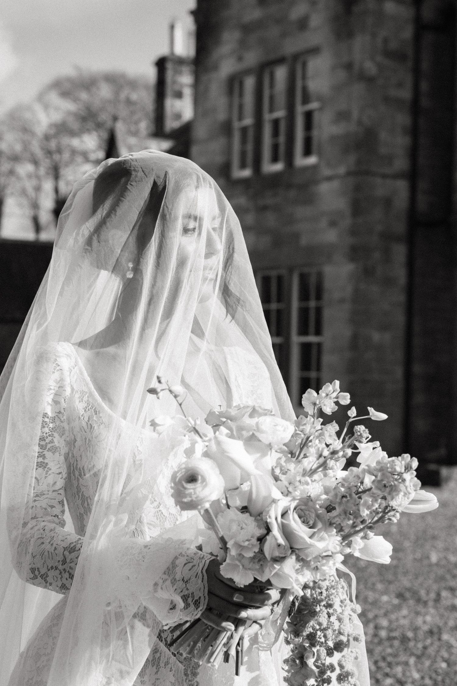 A series of wedding photos showing white veils with delicate lace details against a stone building backdrop.