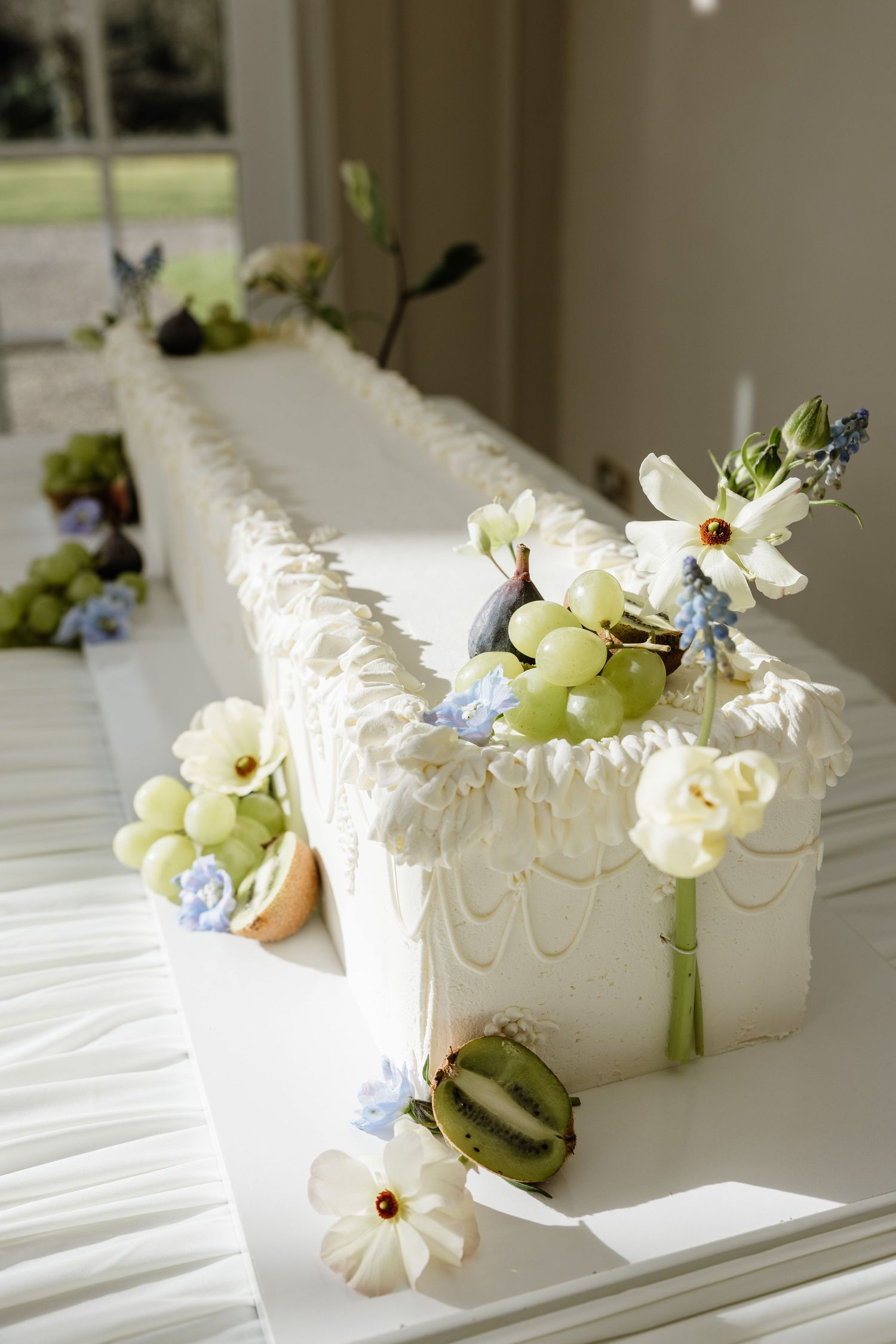 Elegant white floral centerpieces with daisies and blue flowers arranged in small vases on a white tablecloth.