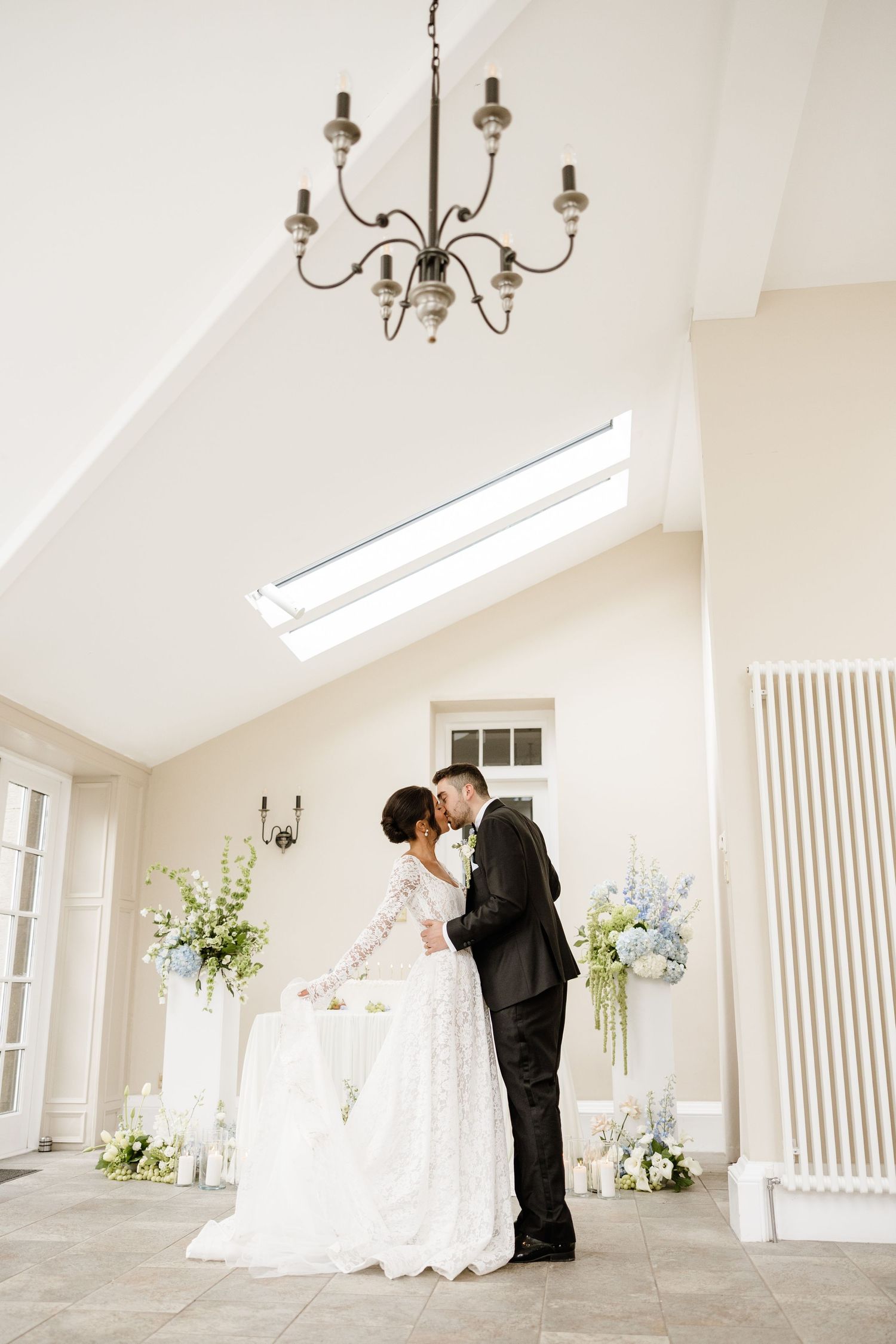 Bright white chapel interior with vaulted ceilings and chandeliers during a wedding ceremony.