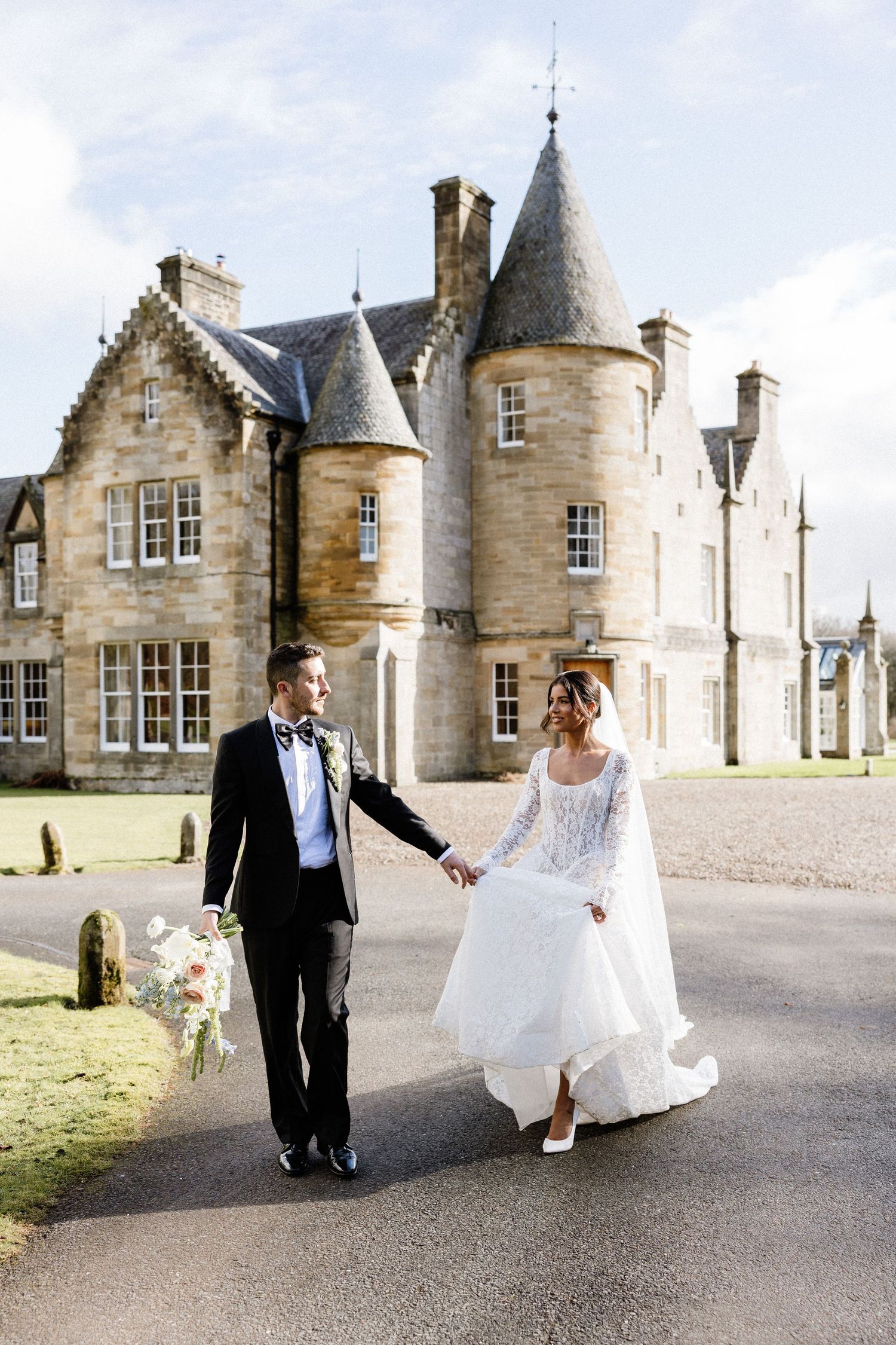 A romantic wedding scene outside a grand Scottish castle with stone turrets and architecture.