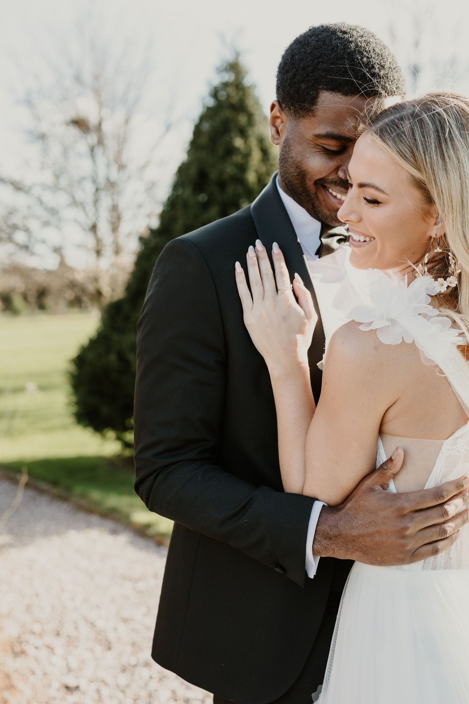 An intimate outdoor wedding portrait showing tender embrace between newlyweds.