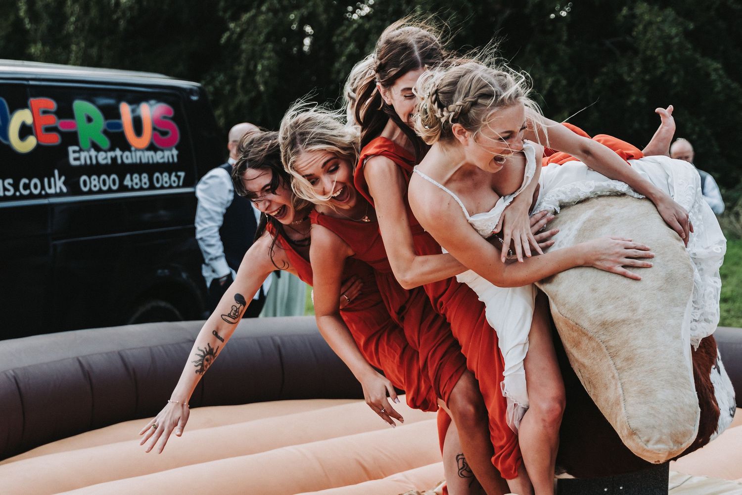Wedding party having fun on bouncy castle entertainment at outdoor reception.
