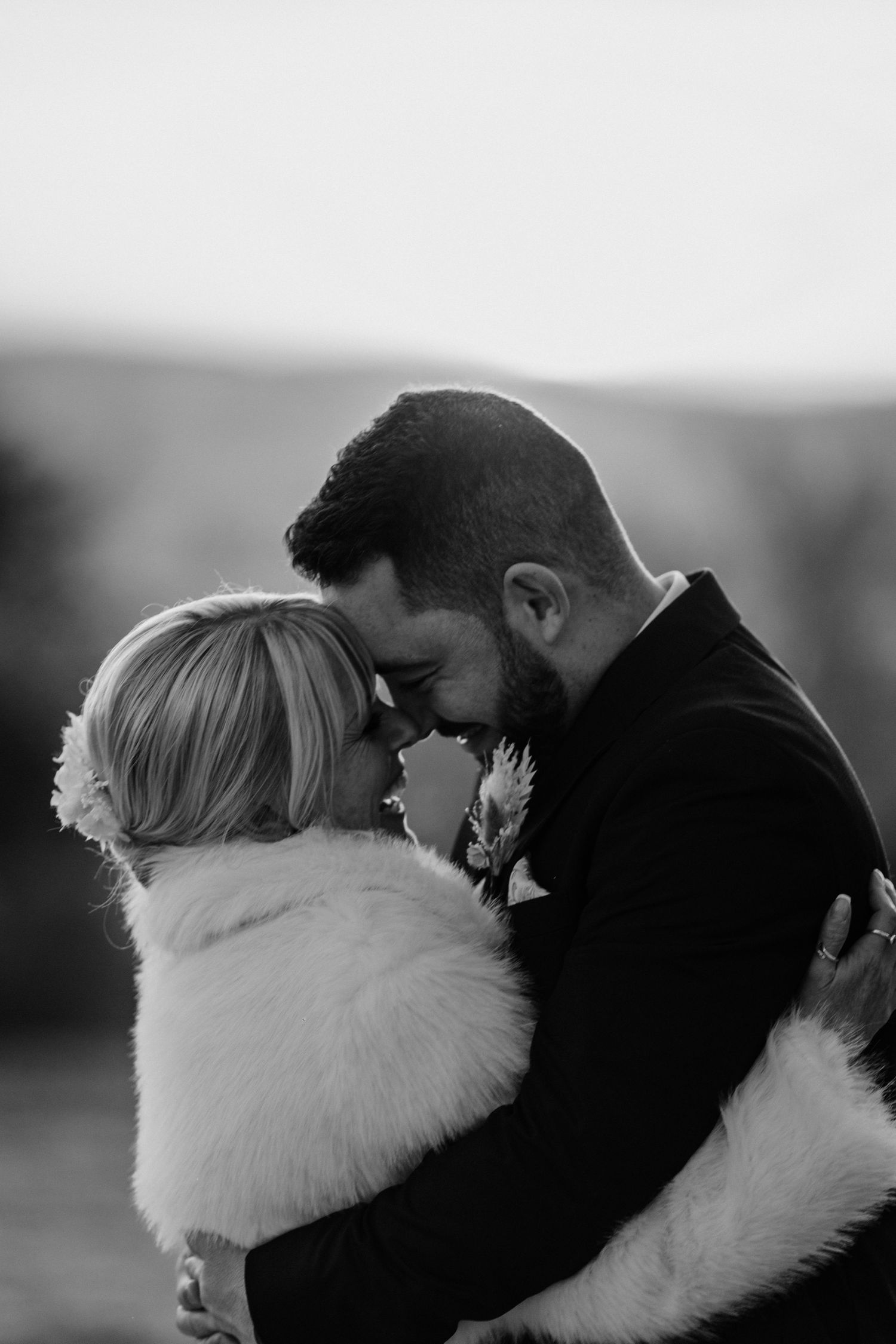 A romantic black and white photo series showing a couple embracing in winter, with one wearing a white fur wrap.