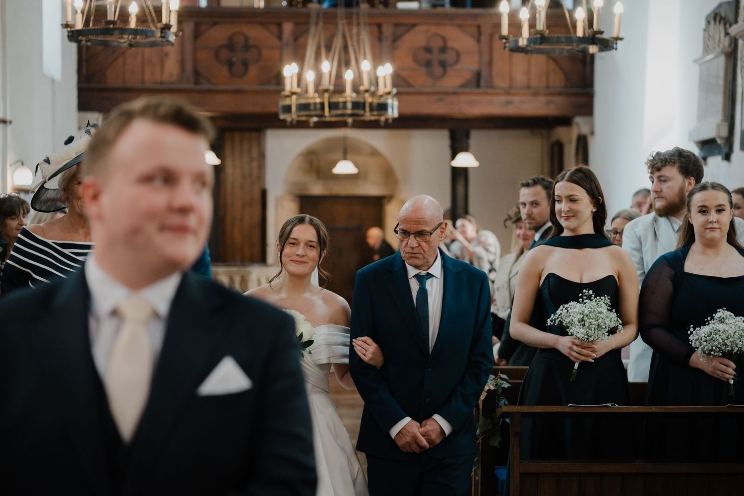 Wedding ceremony inside a traditional church with candlelit wooden interior.