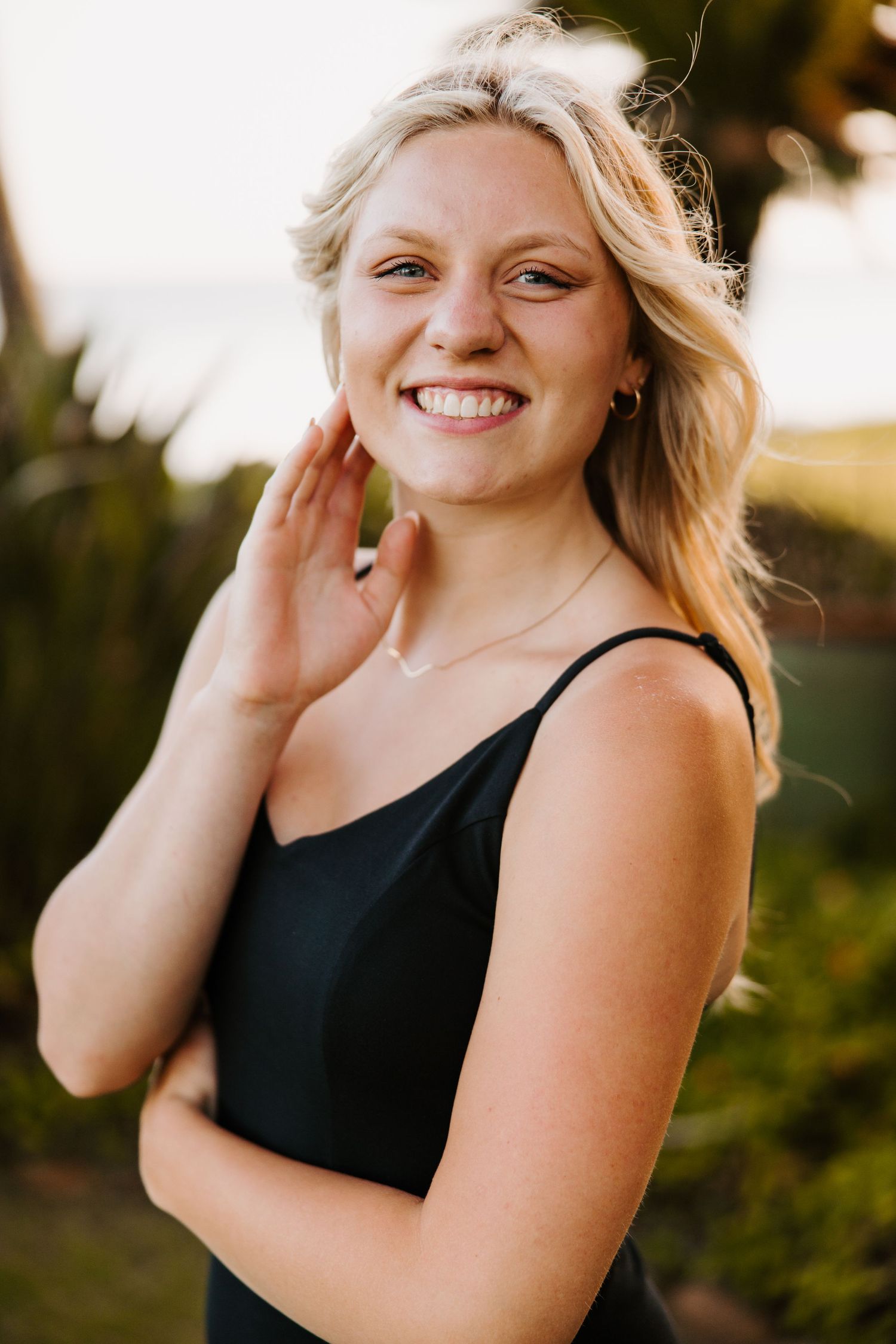Portrait of a wedding, portrait, couple and senior photographer in a black tank top smiling warmly outdoors during golden hour.
