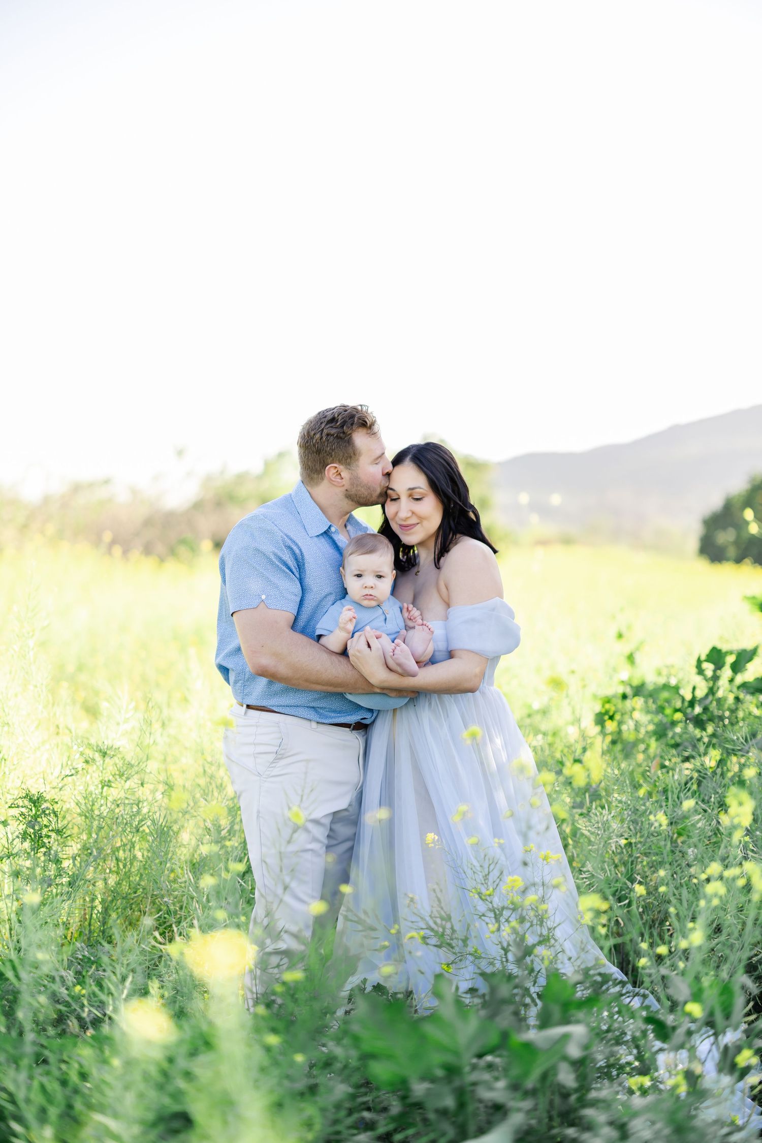 A family stands together in a sunlit meadow filled with wildflowers during golden hour.