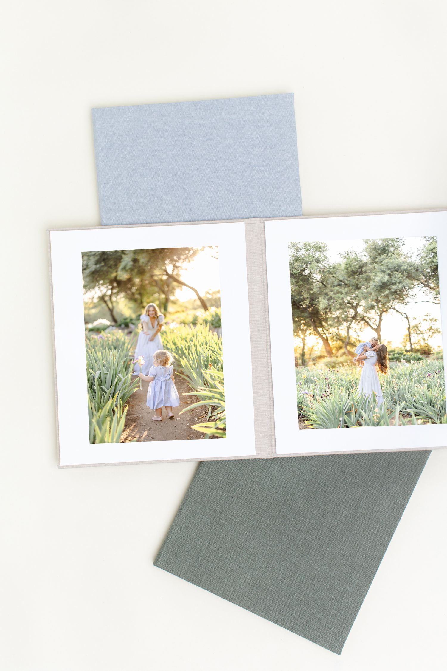 An open photo album displaying garden maternity portraits with linen covers.