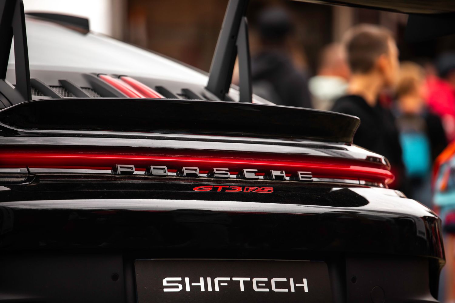 Détail de l’arrière d’une voiture Porsche noire et rouge, avec le logo ShiftTech visible.