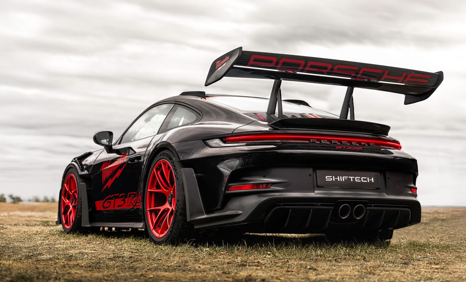 Détail de l’arrière d’une voiture Porsche noire et rouge, avec le logo ShiftTech visible.