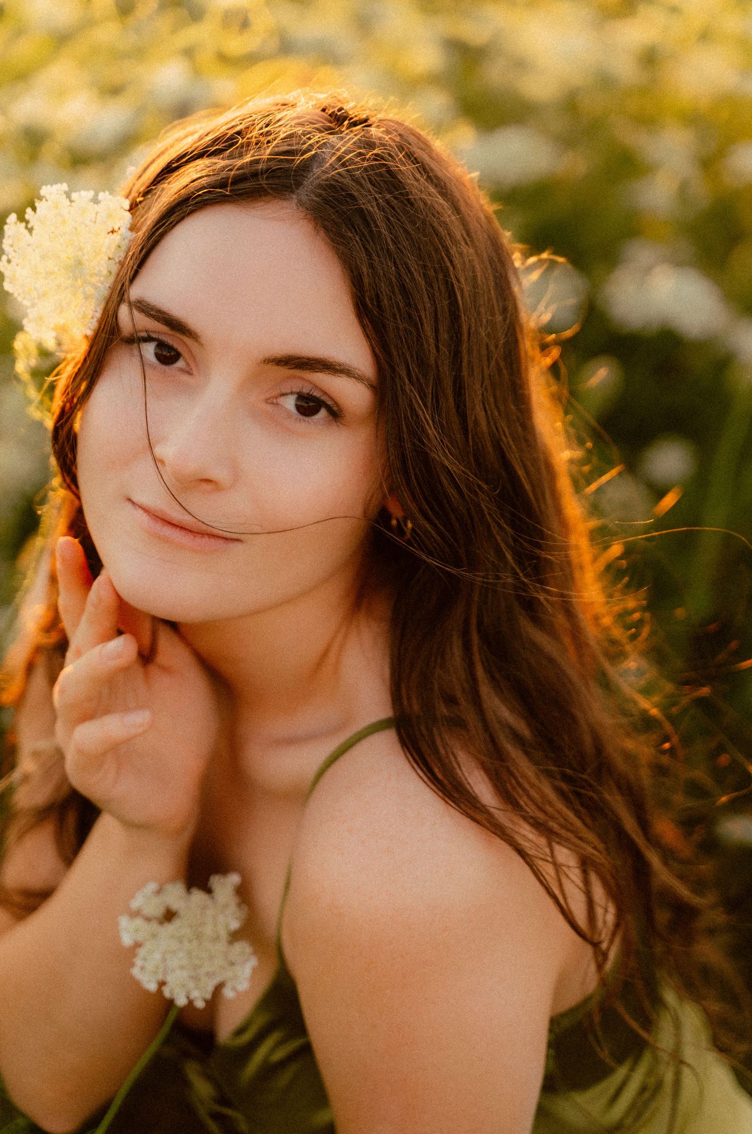 Portrait of a woman with long brown hair in golden sunset light wearing flowers.