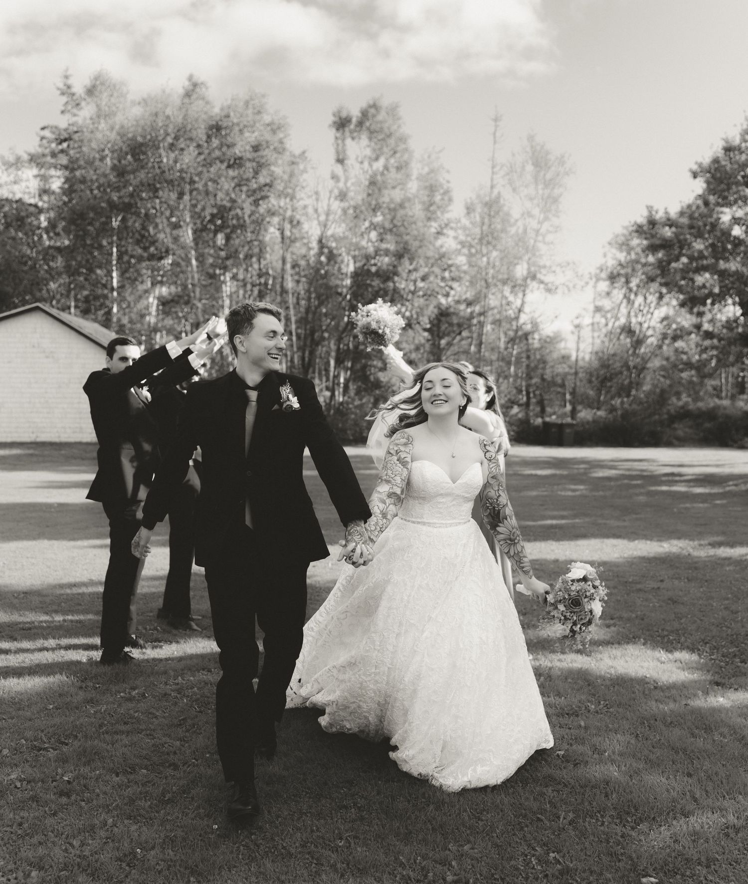 Happy newlyweds walk together joyfully on their wedding day in this vintage black and white photo outdoors.