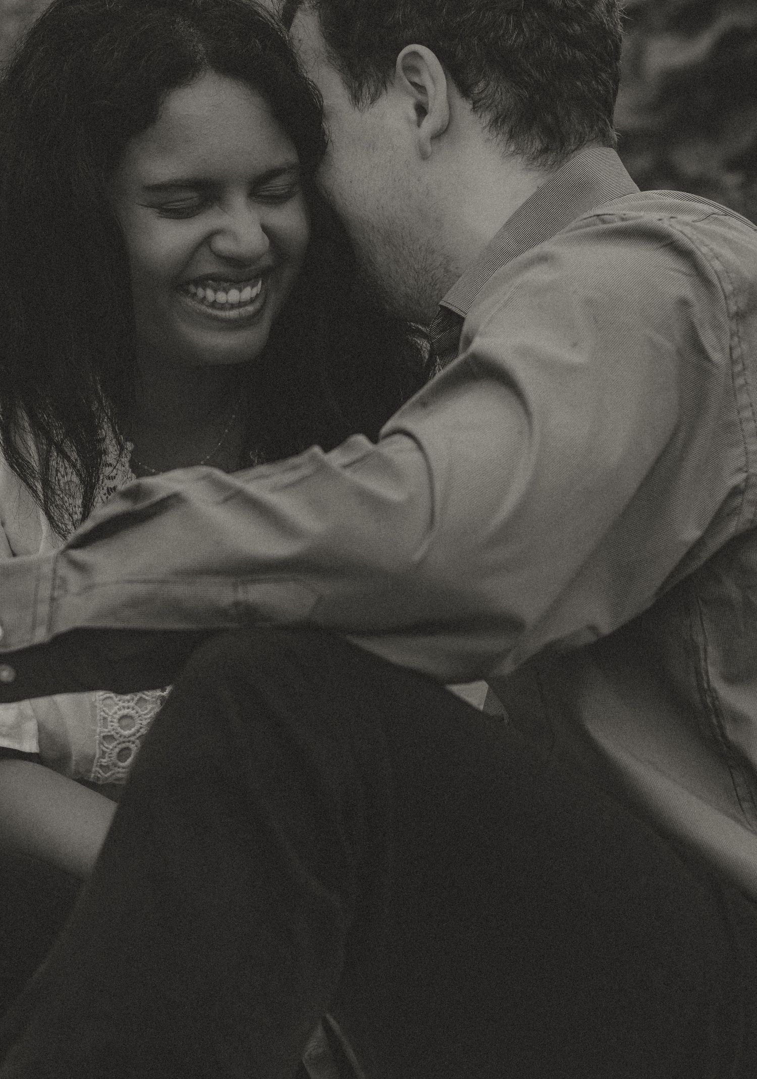 Black and white candid photo of laughing couple sharing intimate moment.