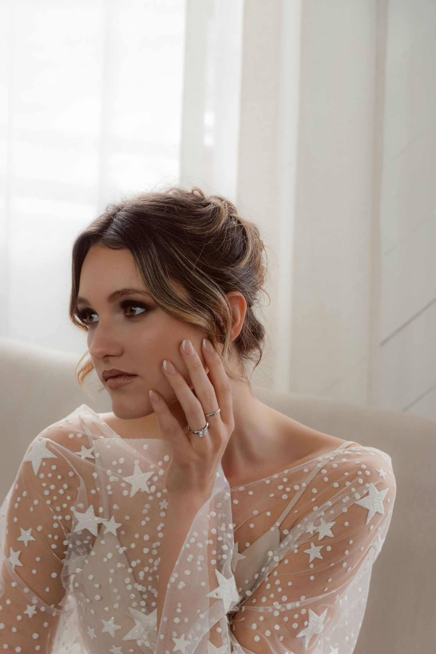 Elegant bridal portrait featuring star-patterned sheer sleeve dress and soft natural lighting.