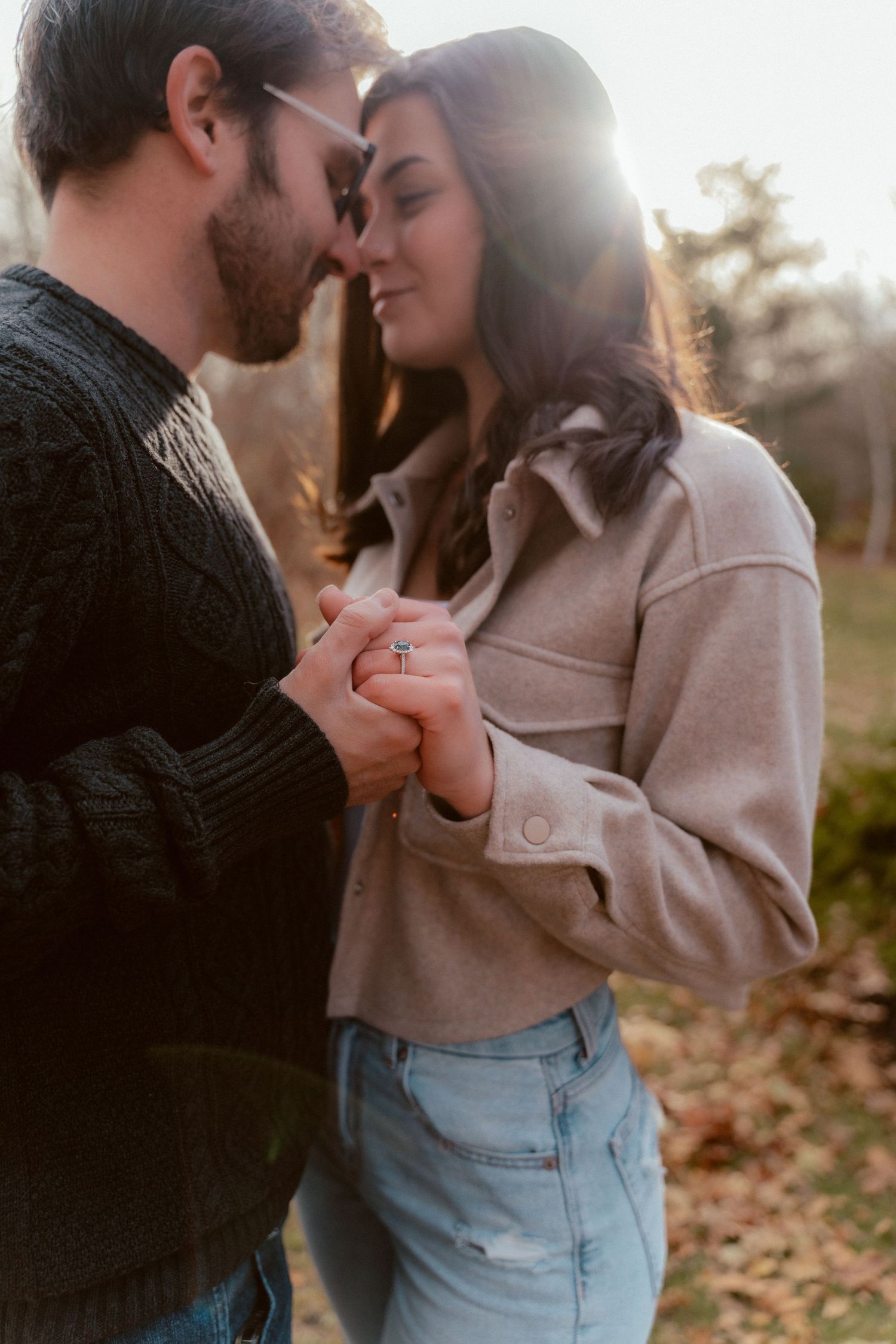 Romantic couple holding hands in warm sunset light while sharing an intimate moment outdoors.