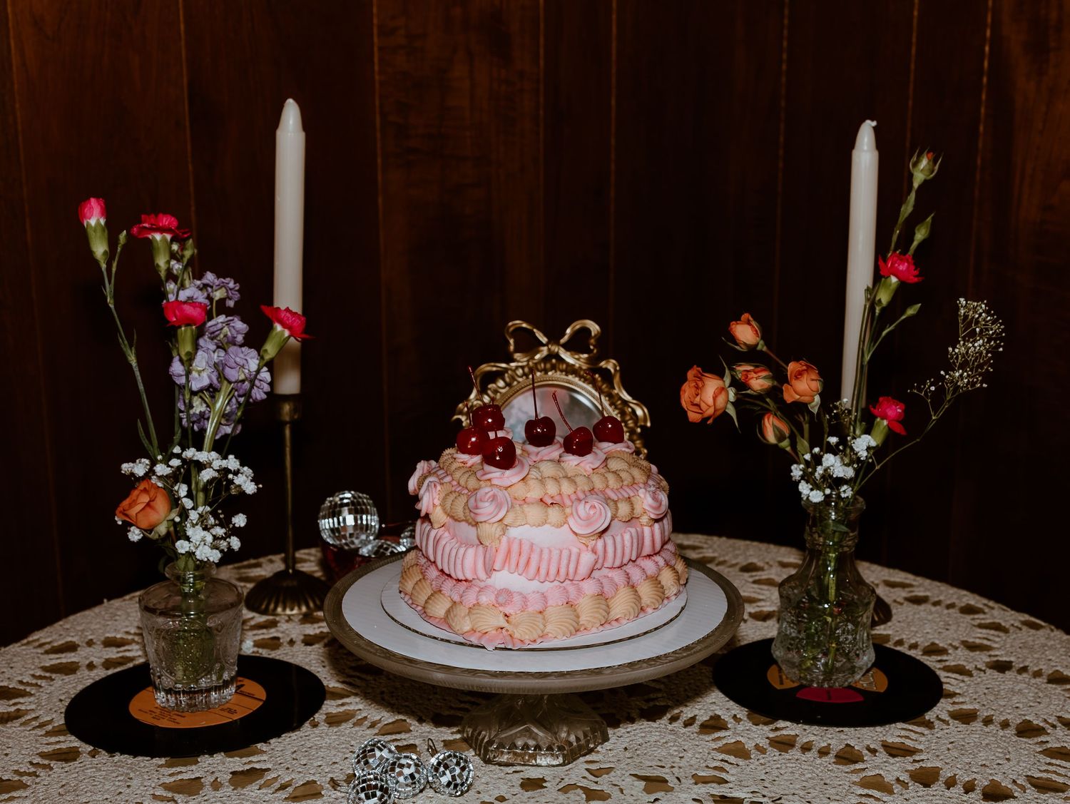 Elegant wedding cake table decorated with delicate flowers and lace doilies at a rustic reception venue.