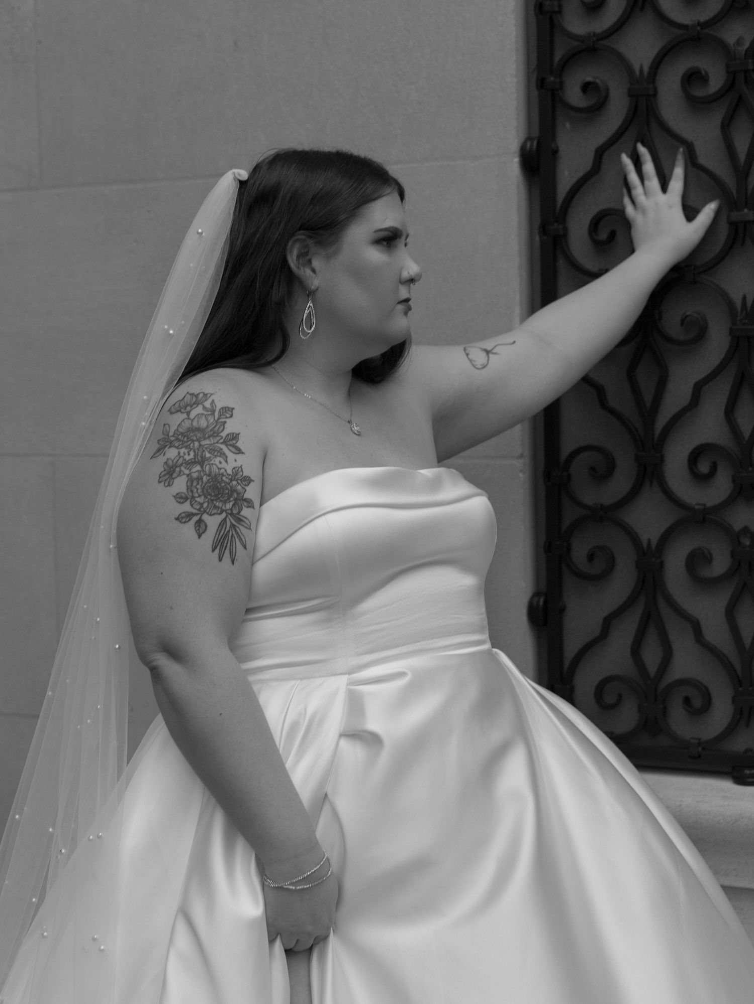 Elegant strapless white wedding gown with flowing train against decorative iron gate.