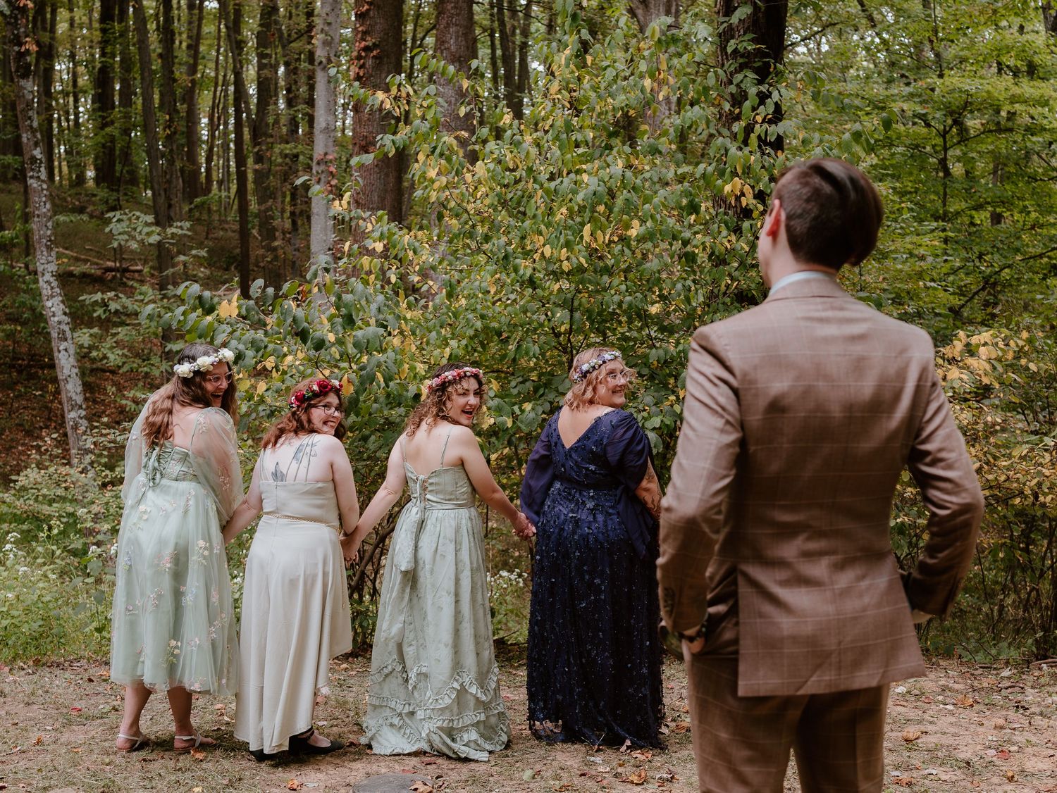 Wedding party walking together through a lush green forest setting.