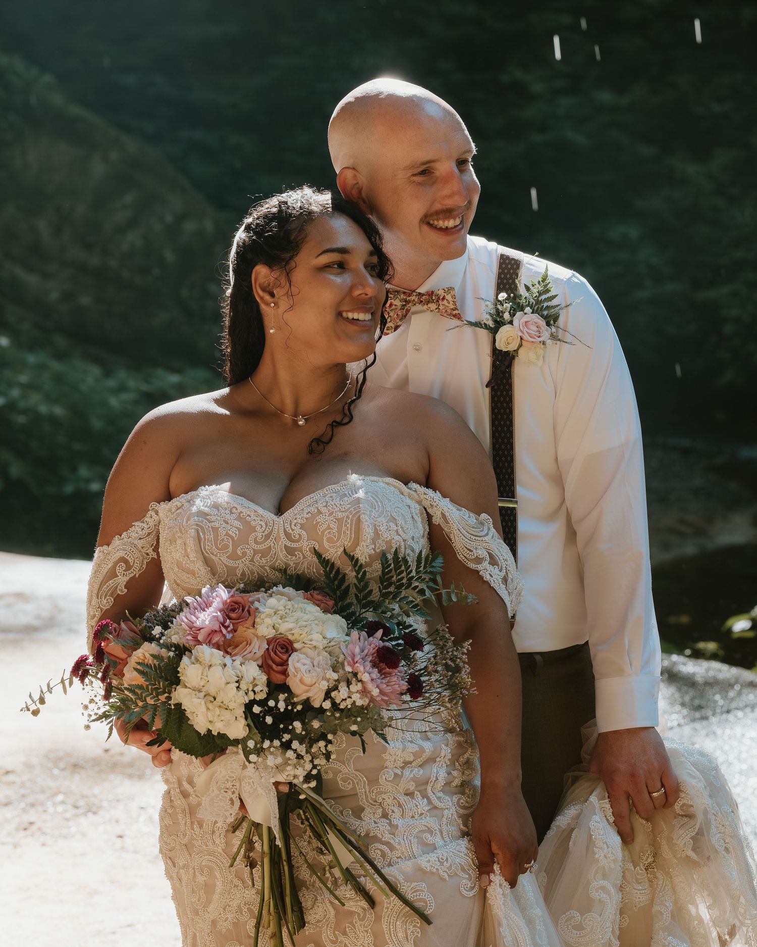 Newlyweds laughing together while holding a romantic floral bouquet.