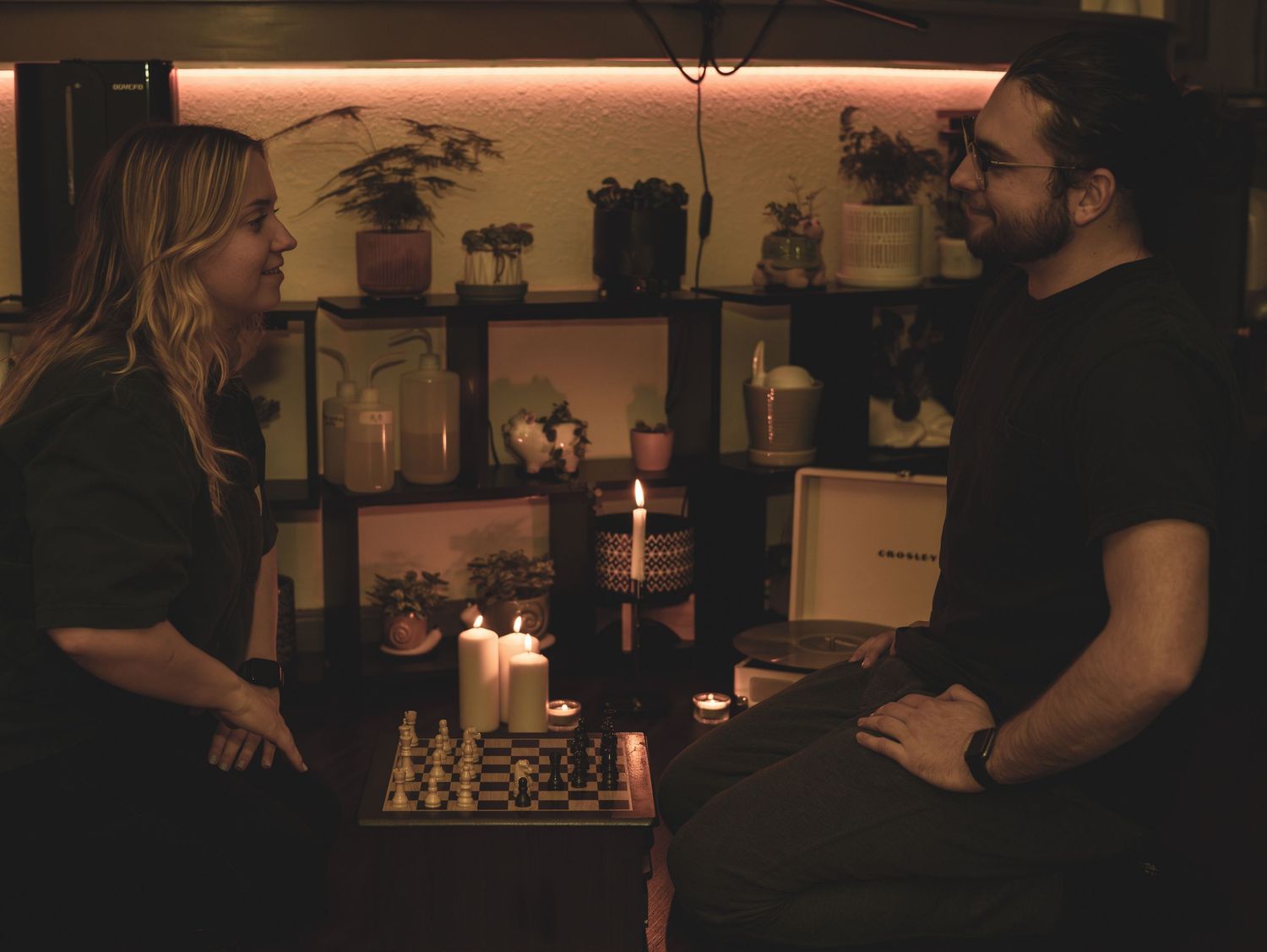 Two people playing chess by candlelight in a dimly lit room creating an intimate gaming atmosphere.
