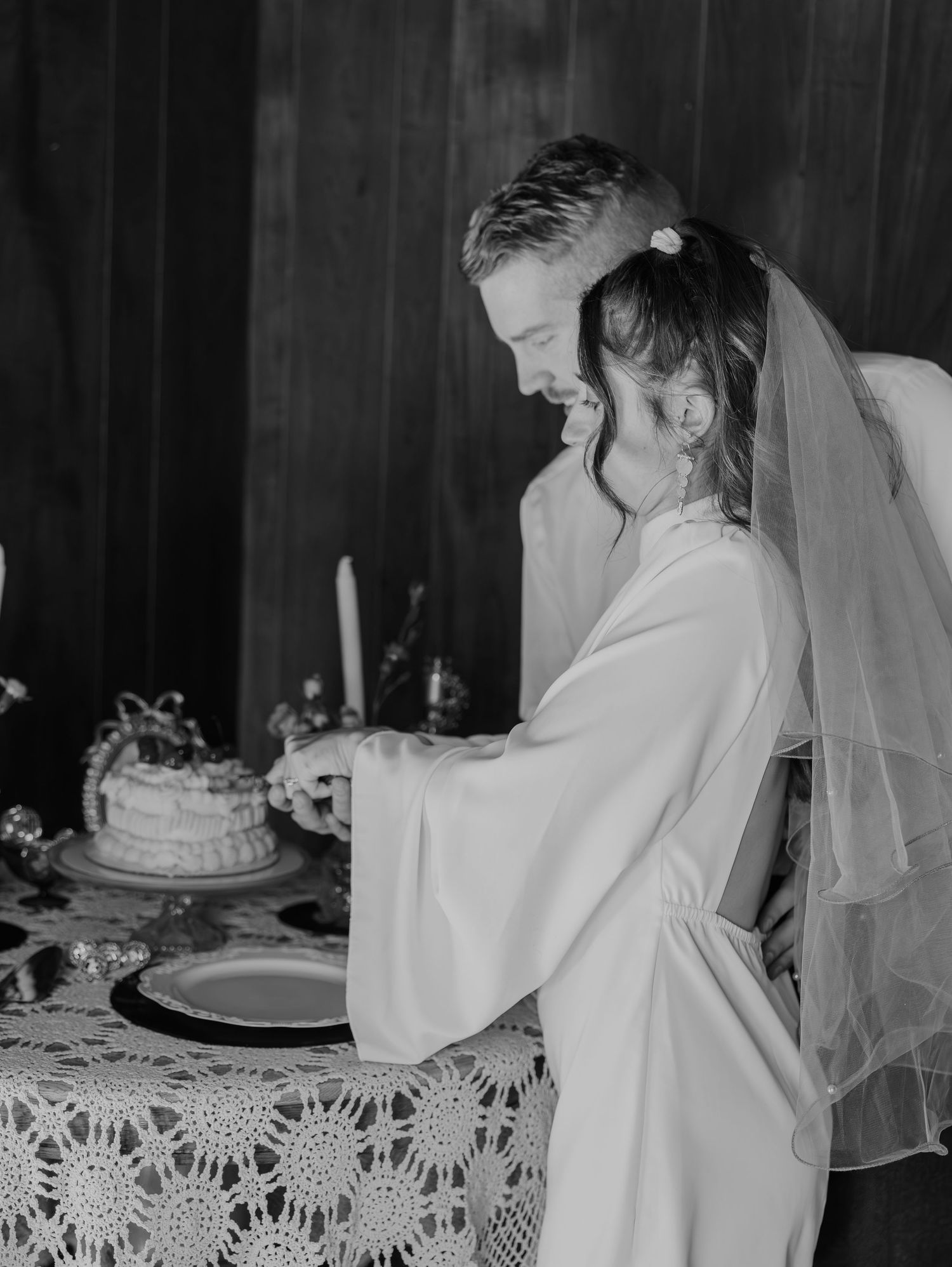A series of black and white wedding photographs showing a bride crying with emotion while looking at her wedding cake.