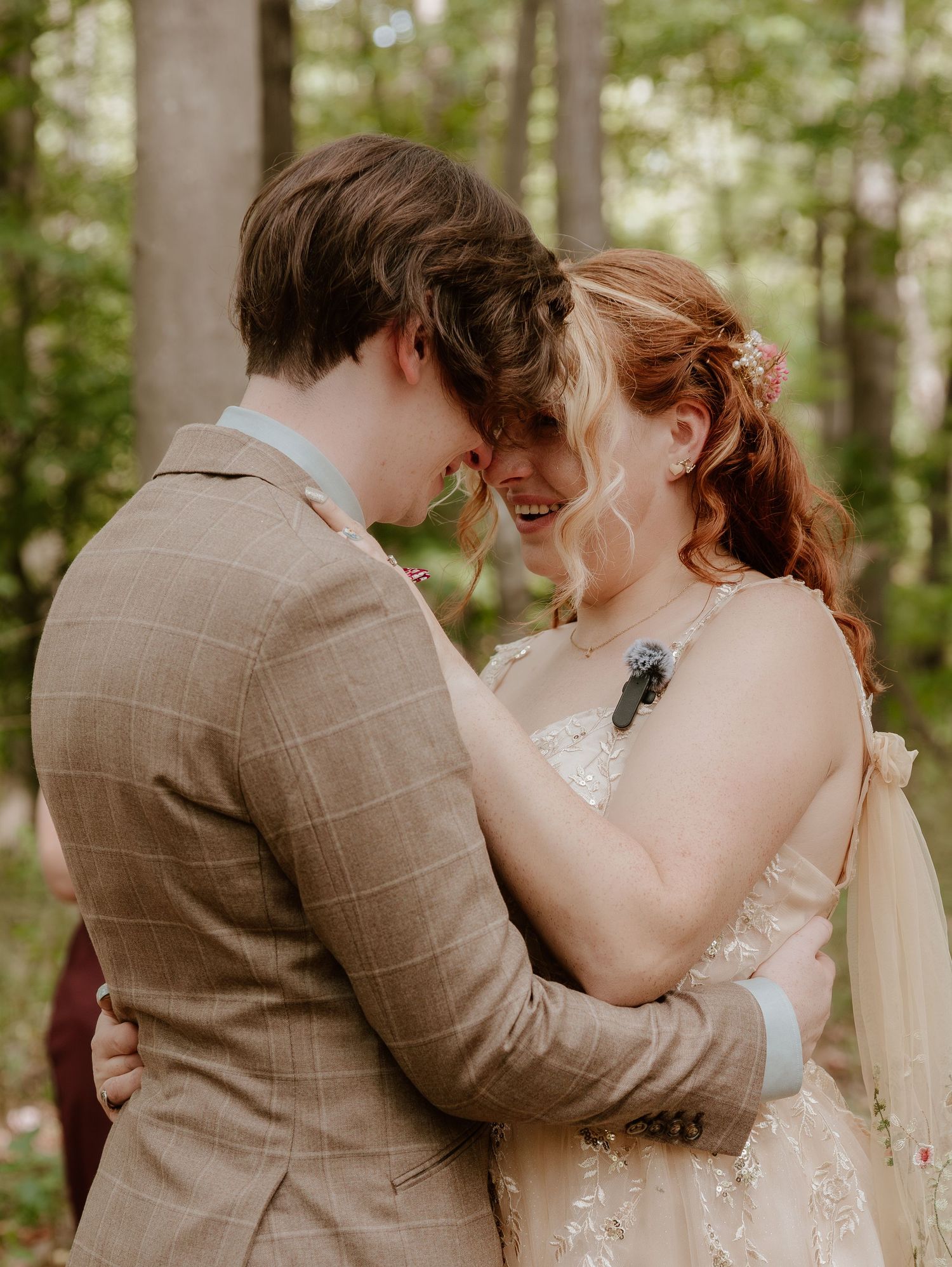 Intimate wedding portrait showing tender moment between couple in woodland setting.