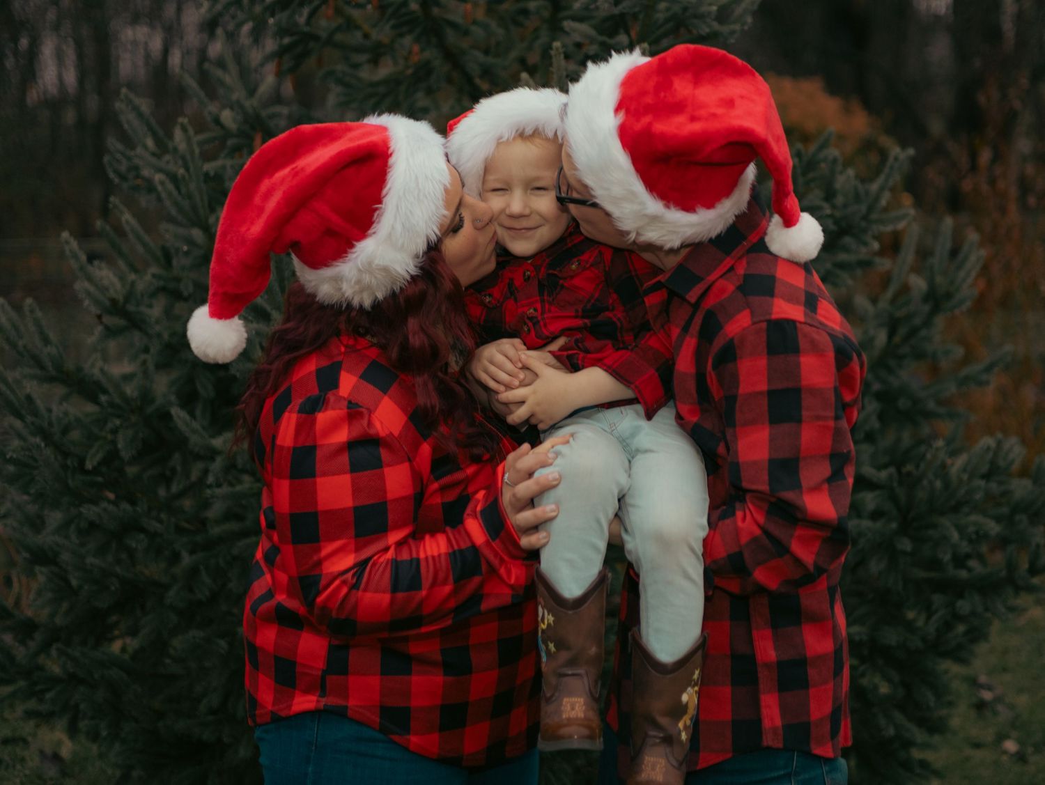 A festive holiday photo featuring buffalo plaid shirts and Santa hats in an outdoor setting.