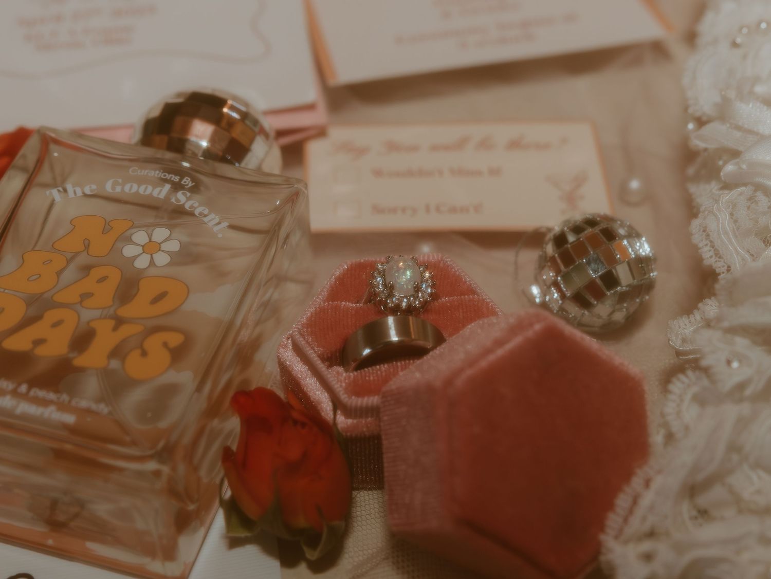 Perfume bottle collection and rose petals arranged on a romantic pink surface with soft lighting.