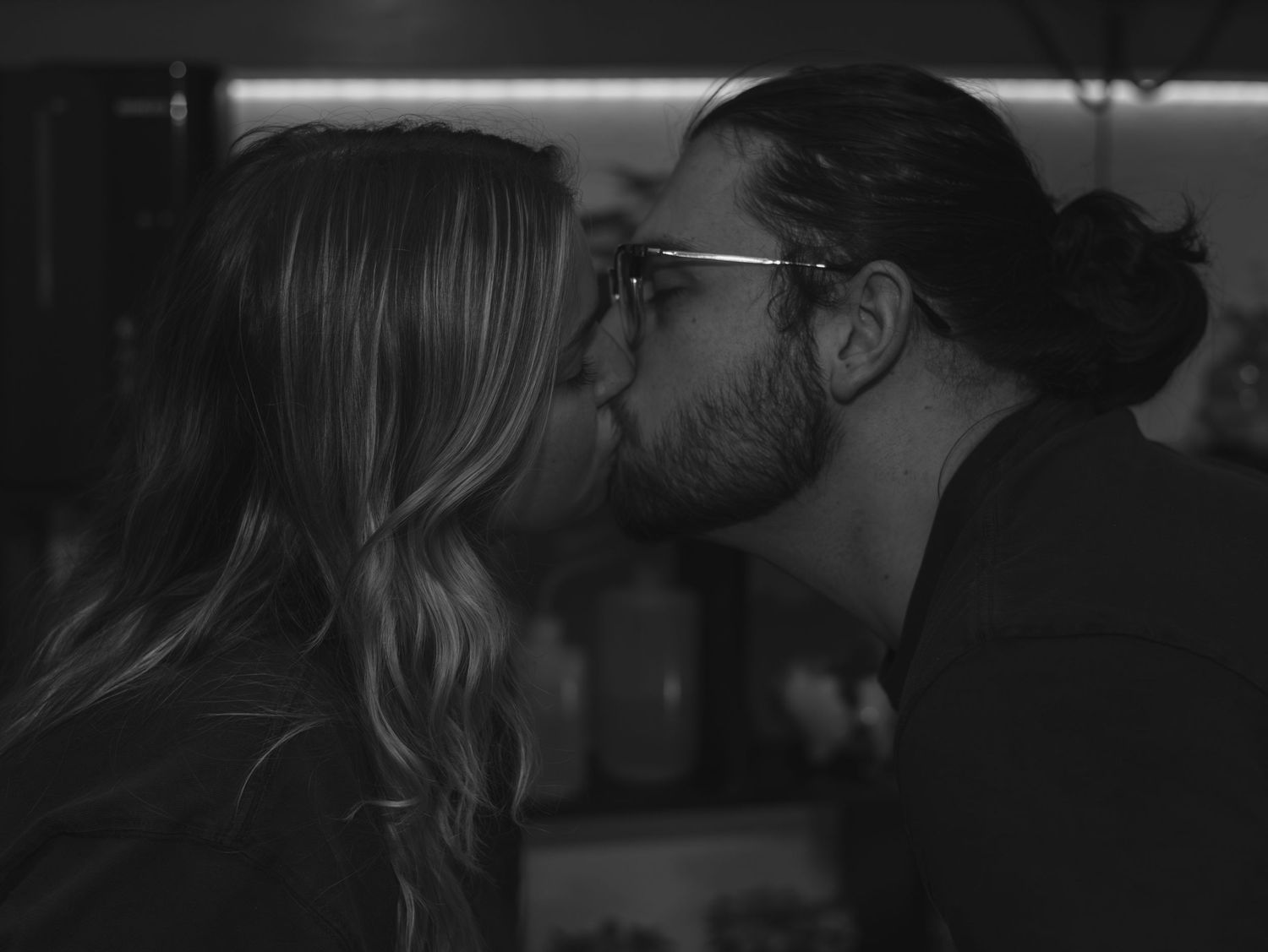 Black and white romantic scene showing couple in silhouette sharing an intimate kiss.