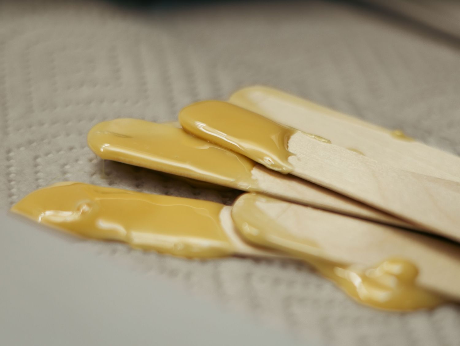 A slice of cheese being peeled off in close-up detail against a light background.