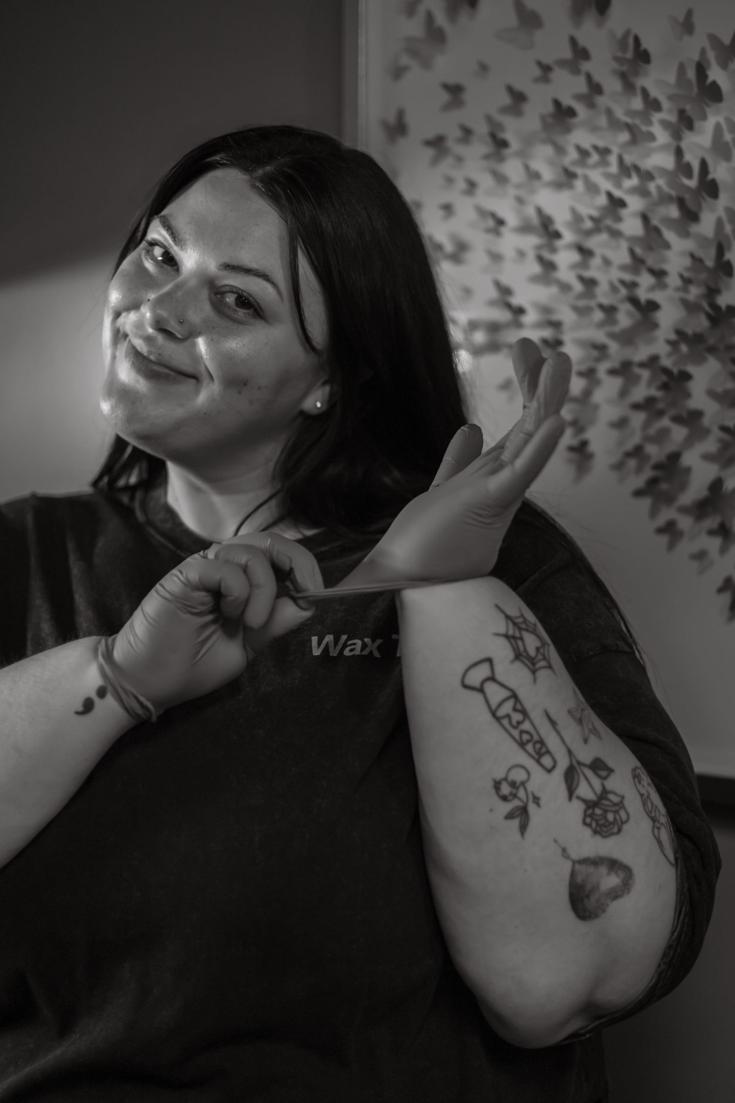 Black and white images show expressive poses with hand gestures against backdrop of butterfly wall decorations.