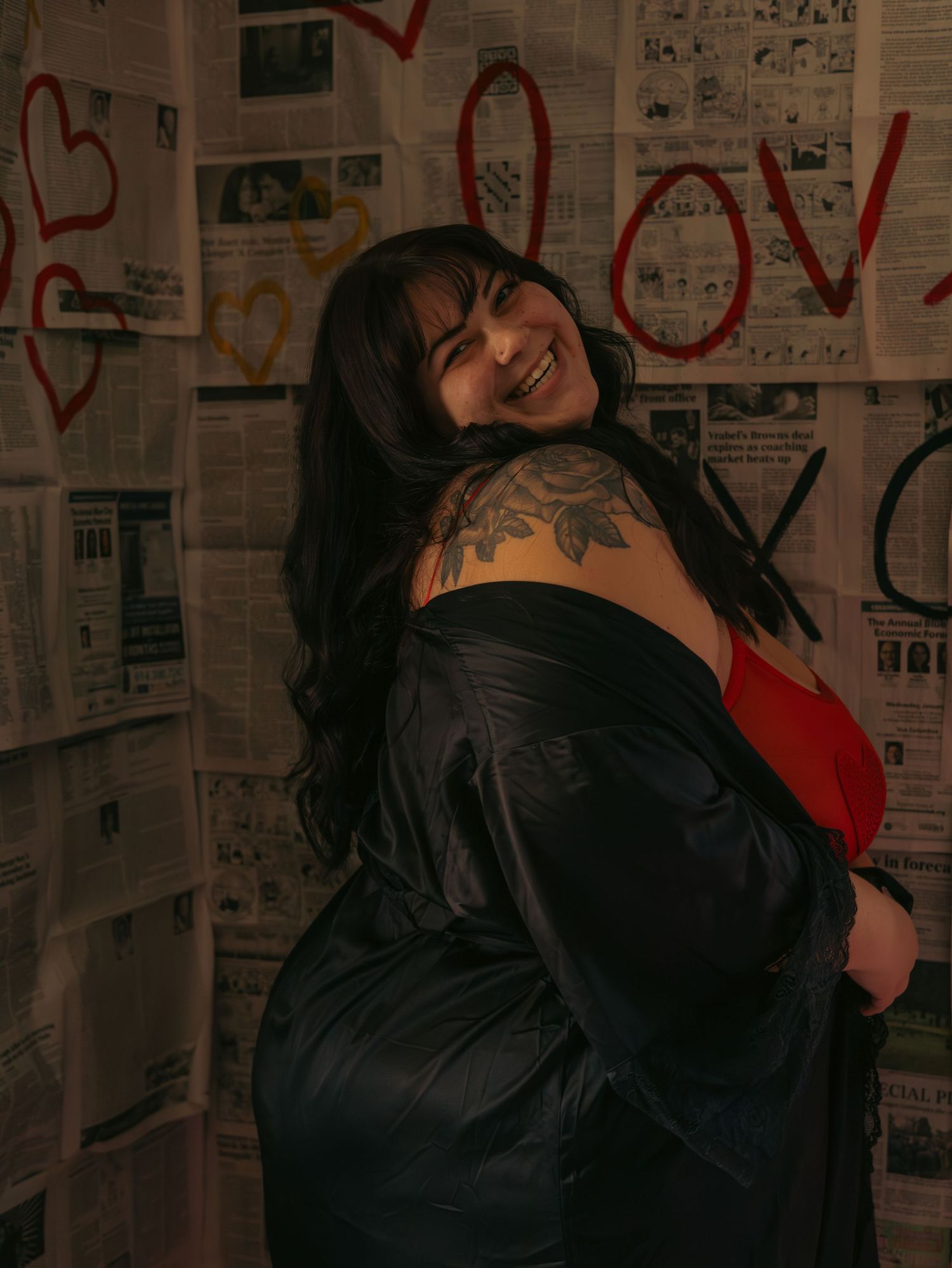 A silhouette stands against a wall covered in graffiti and love messages in a dimly lit setting.