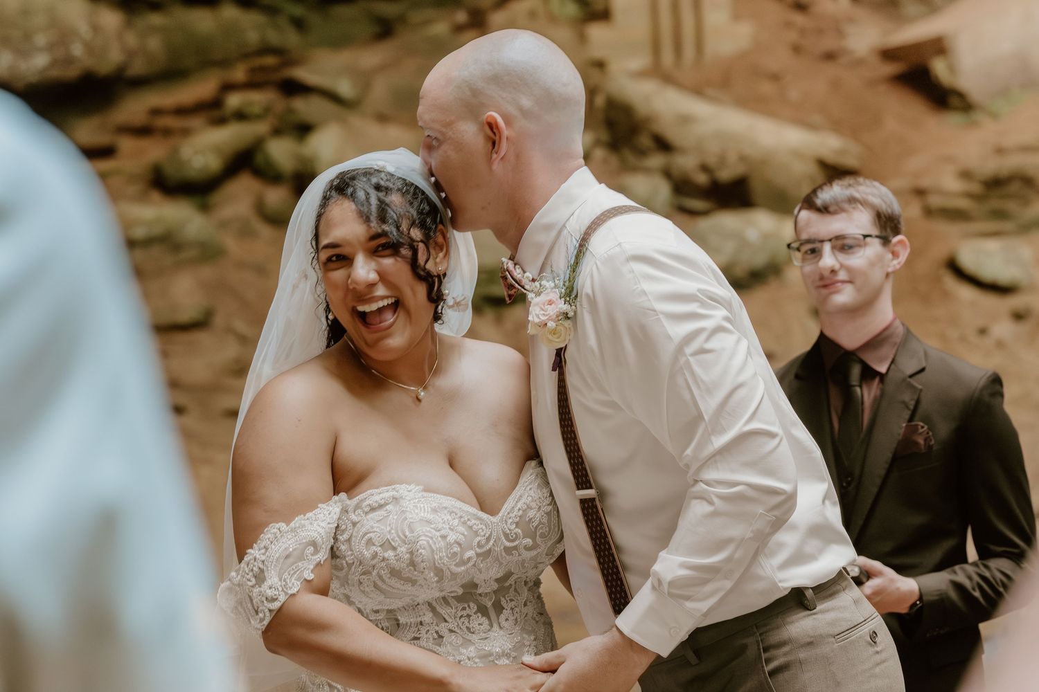 A couple shares an intimate moment during their wedding ceremony in a rustic outdoor setting.