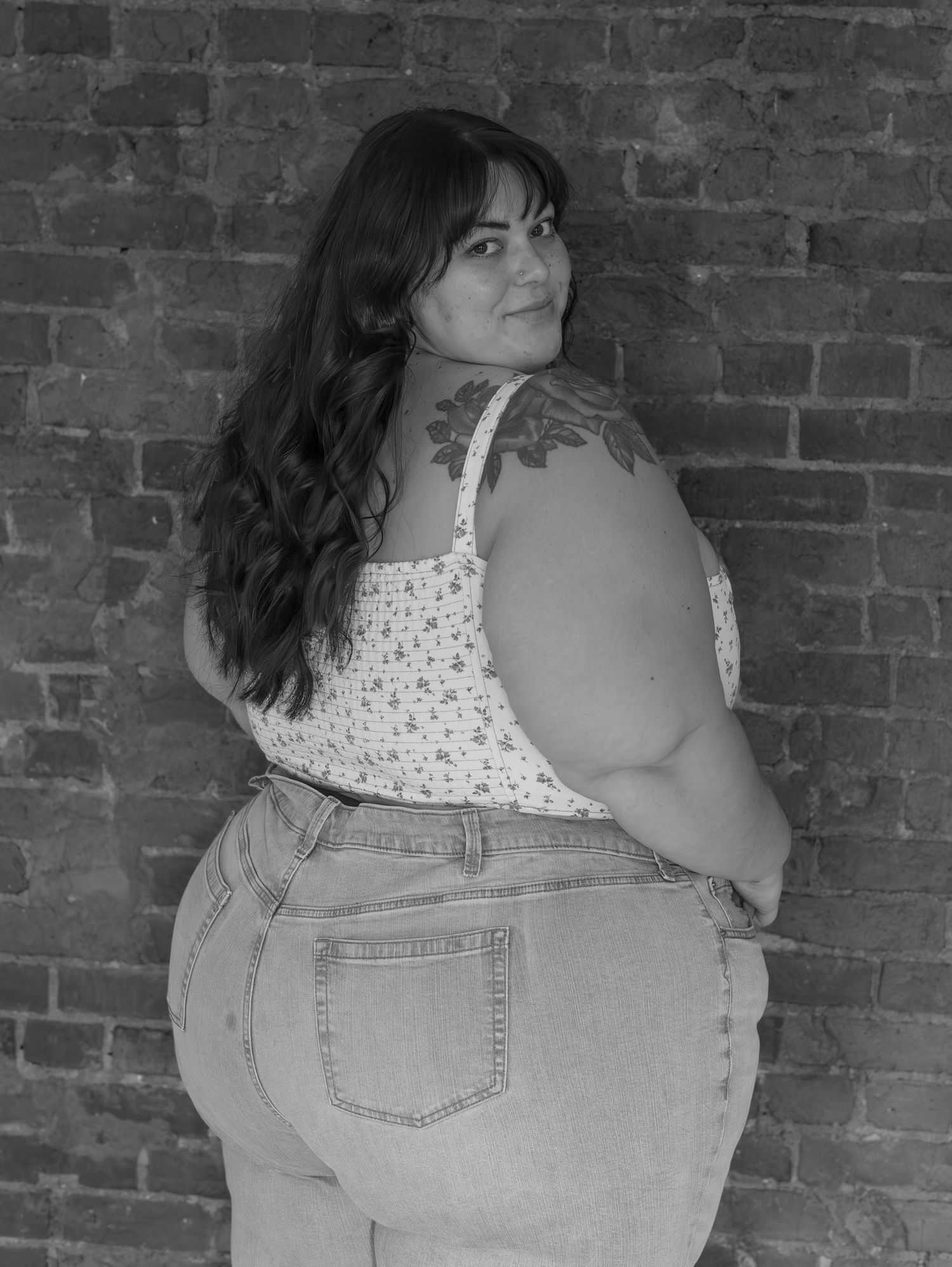 Black and white portrait series against brick wall showing dynamic poses in denim and white patterned top.