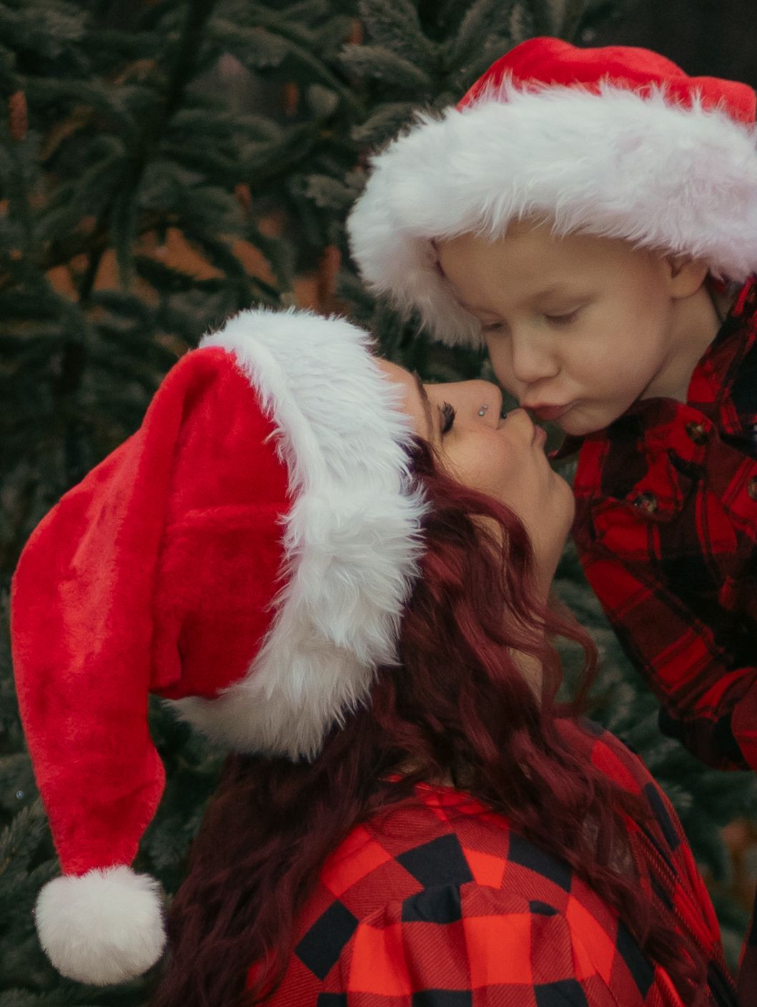 A tender holiday moment captured between two people wearing Santa hats and buffalo plaid.