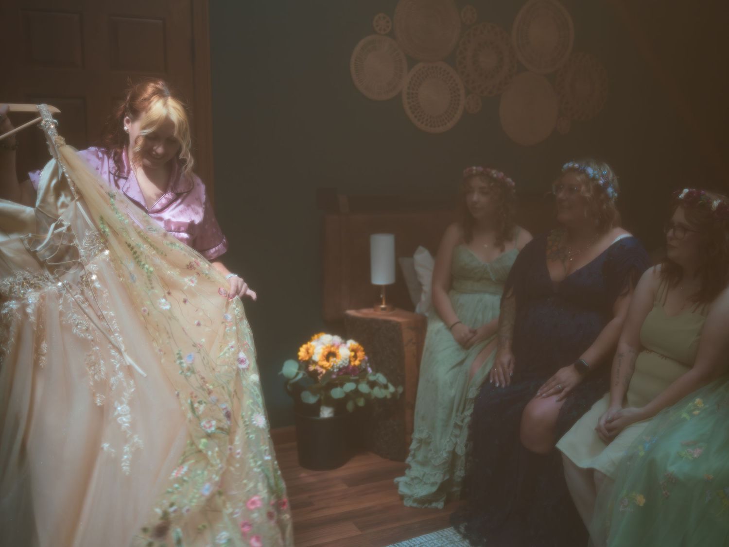 Wedding party members admire a beautiful white lace gown on display at an indoor venue.