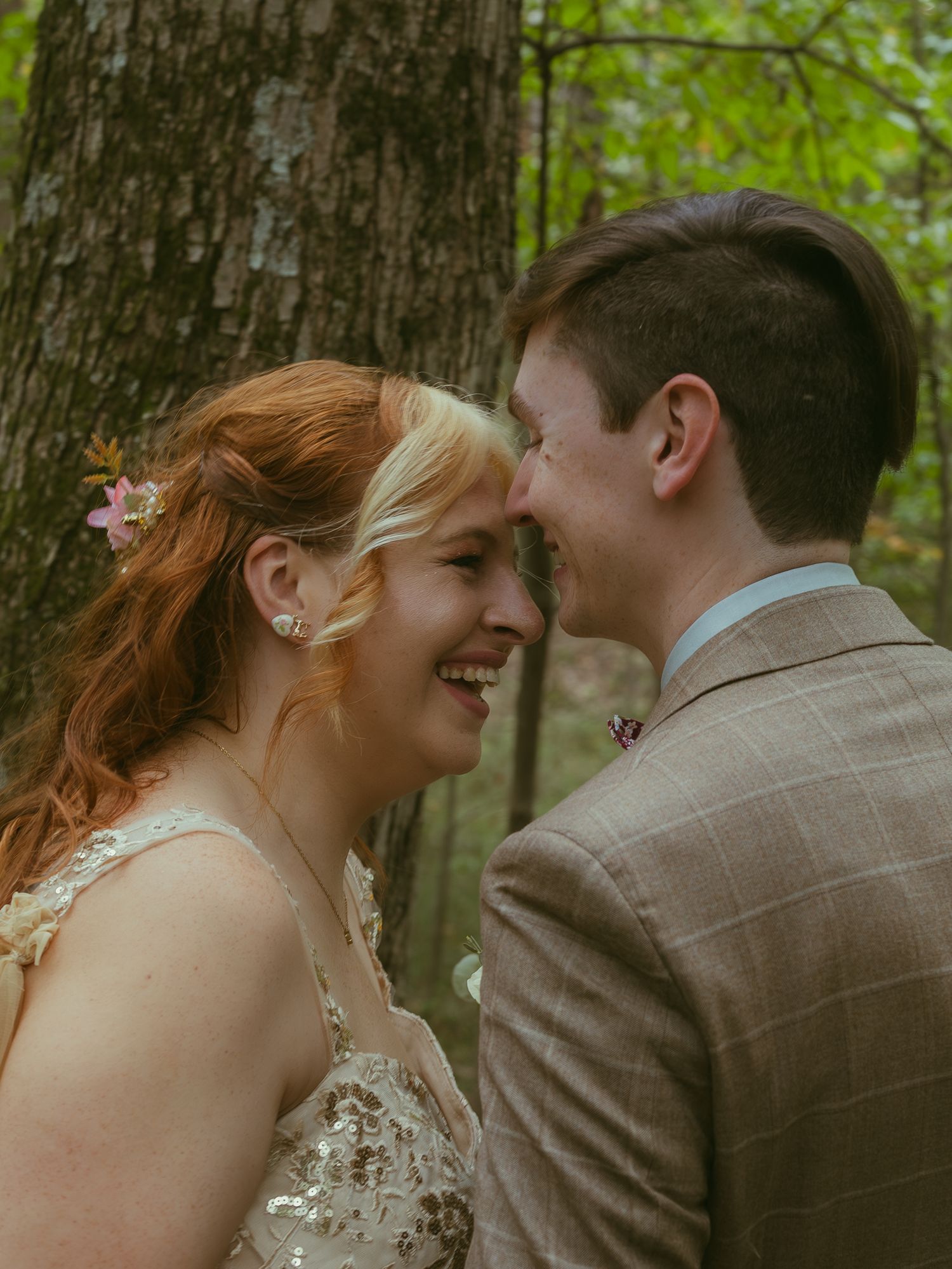 Intimate forest wedding moment between couple in tan suit and champagne dress.
