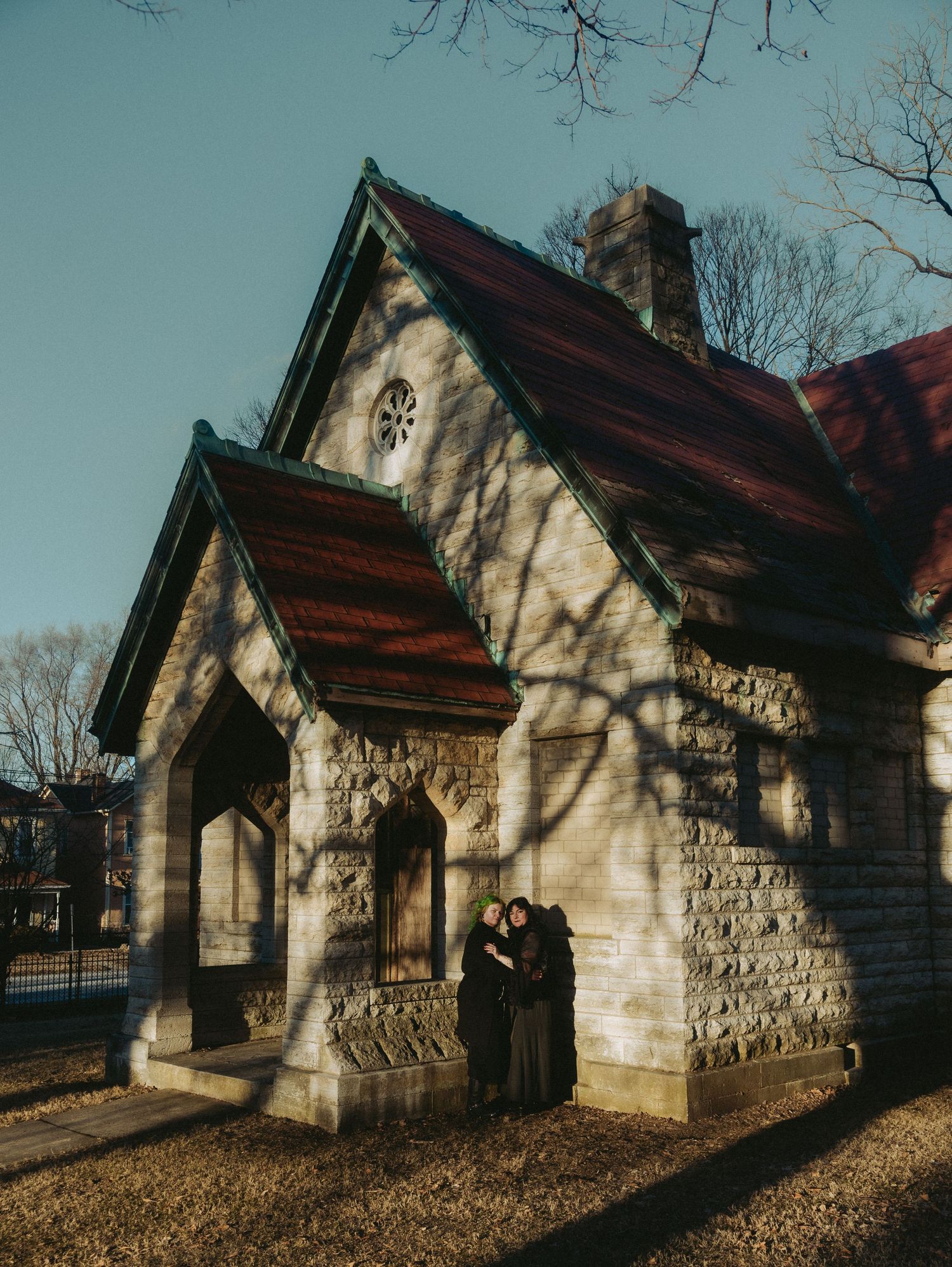 Row of small stone chapel buildings with peaked roofs casting long shadows on a sunny winter day.
