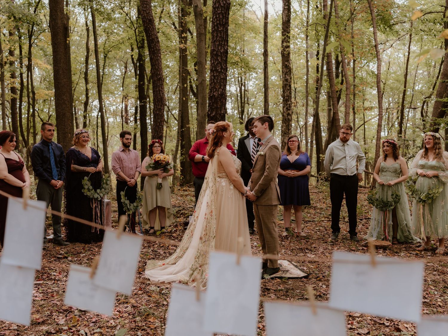 Wedding party members gather for photos in a serene wooded setting.