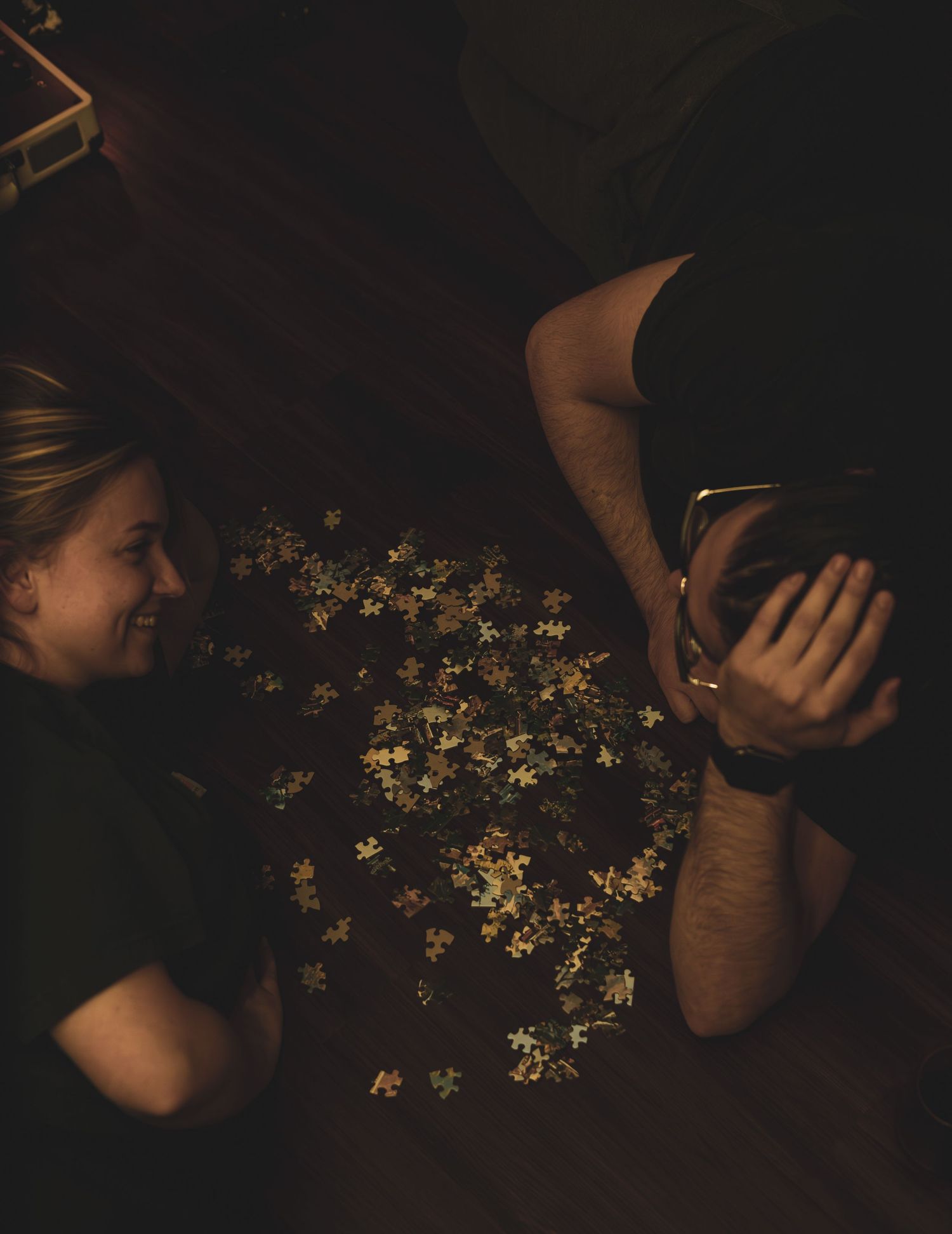 Dark moody still life photograph showing scattered small white flowers against a black background.