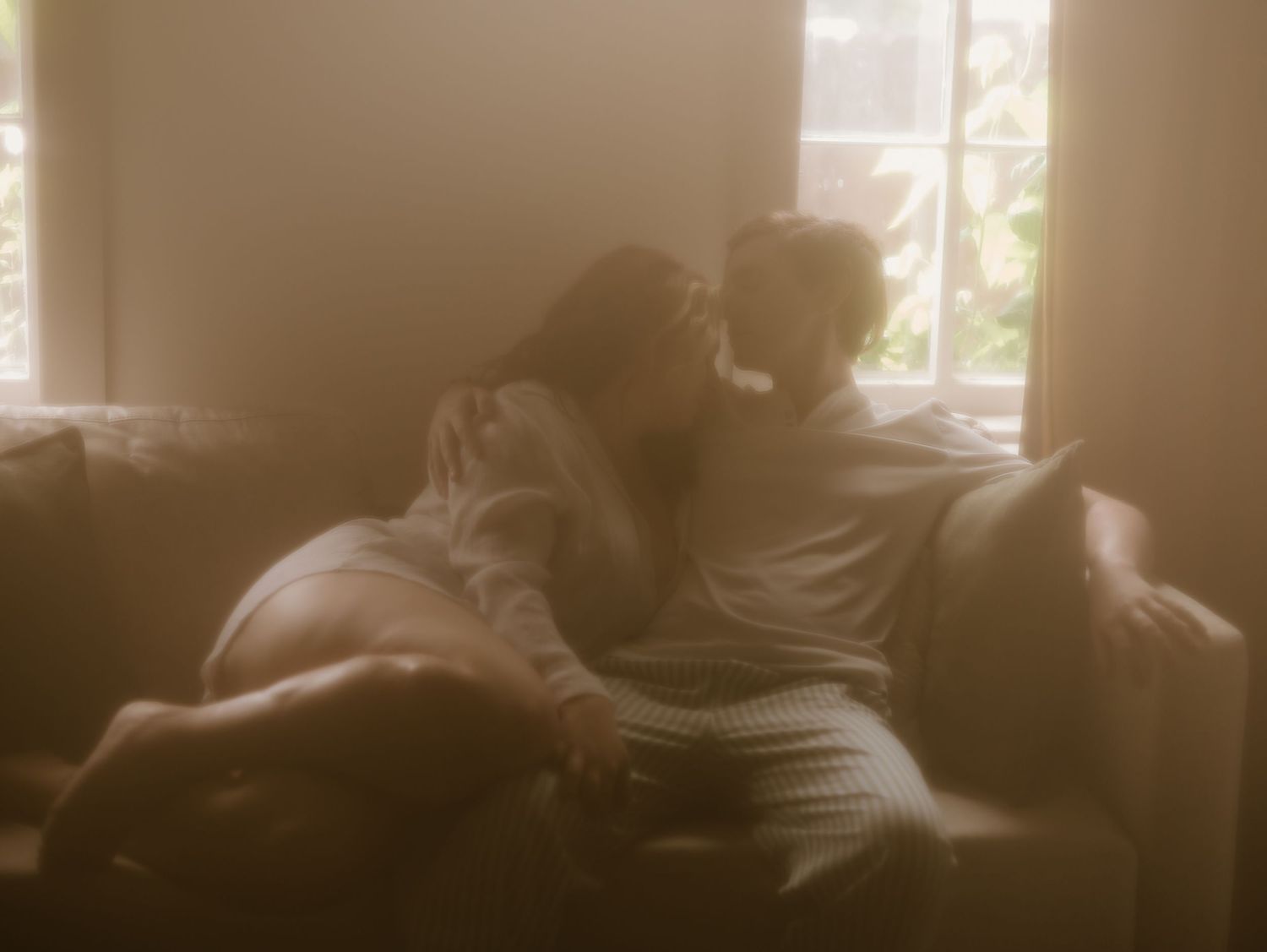 A dimly lit room with sunlight streaming through windows creates a moody, atmospheric interior scene.