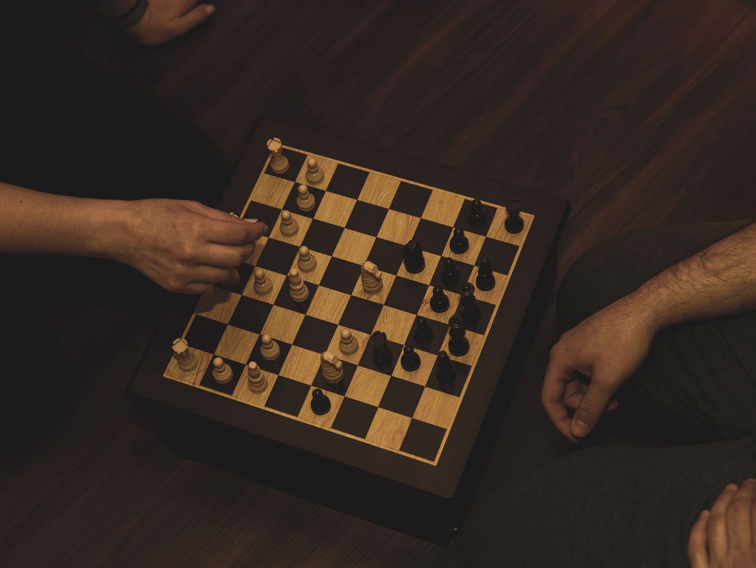 Multiple hands move chess pieces across a chessboard in a sequence of strategic gameplay photos.