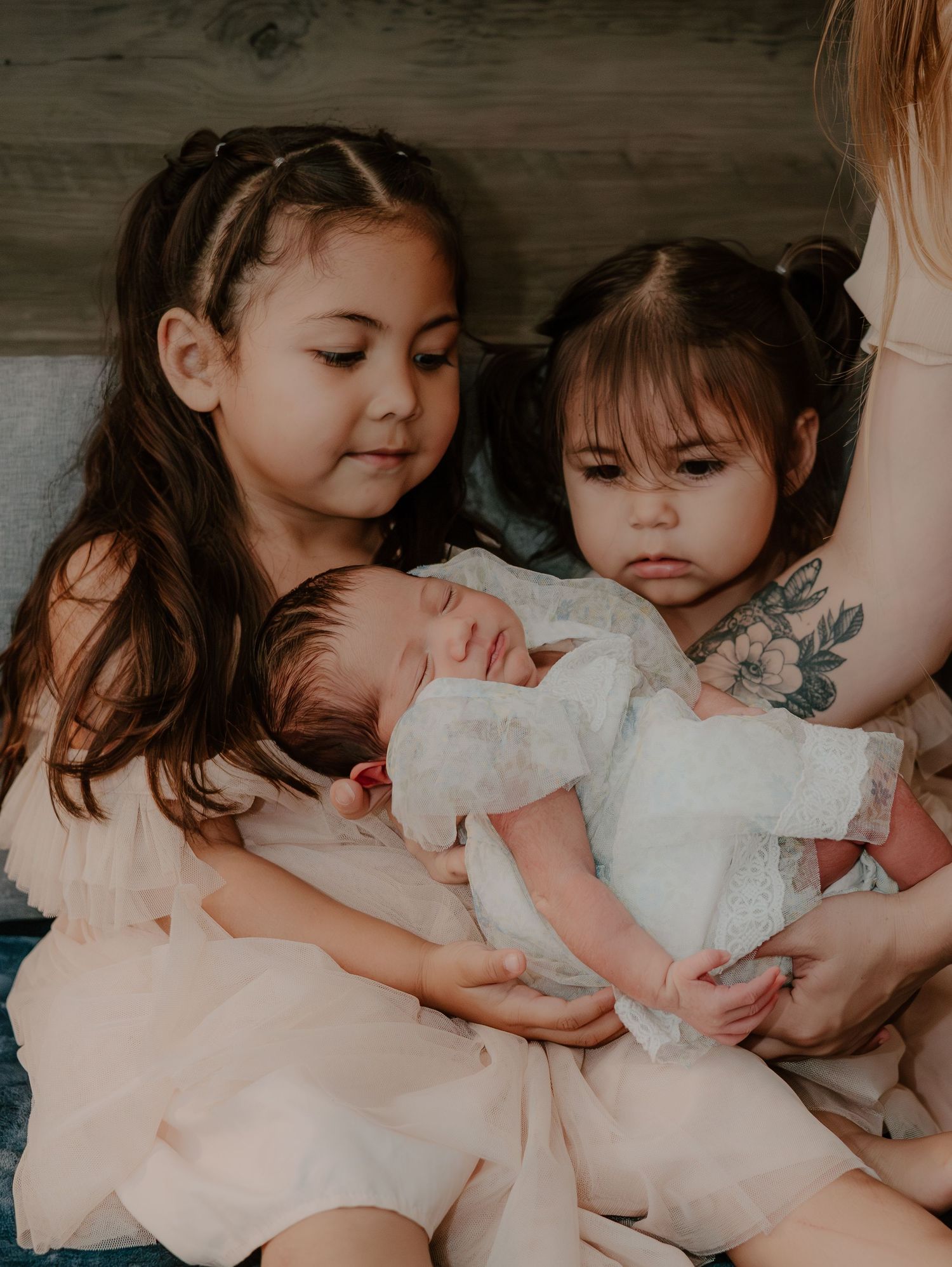 Young children in white dresses gather around a newborn baby.