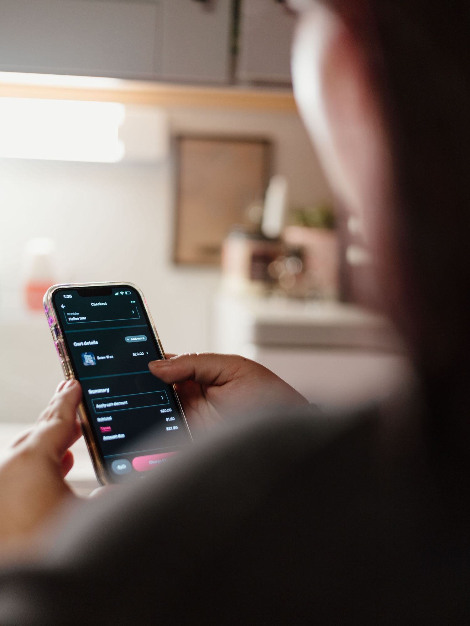 Person looking at a mobile phone screen showing a dark interface in a dimly lit room.