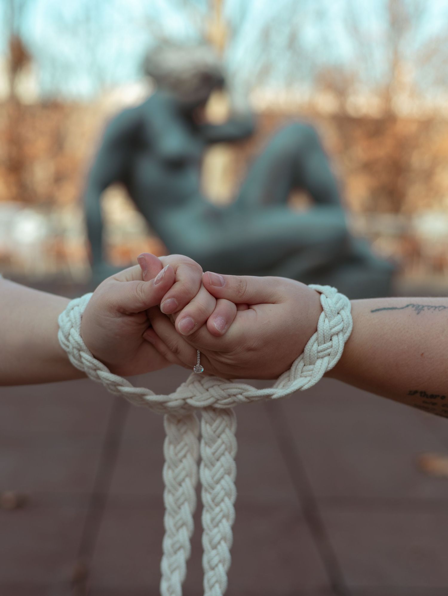 Hands holding braided white rope in handfasting ceremony against outdoor background.