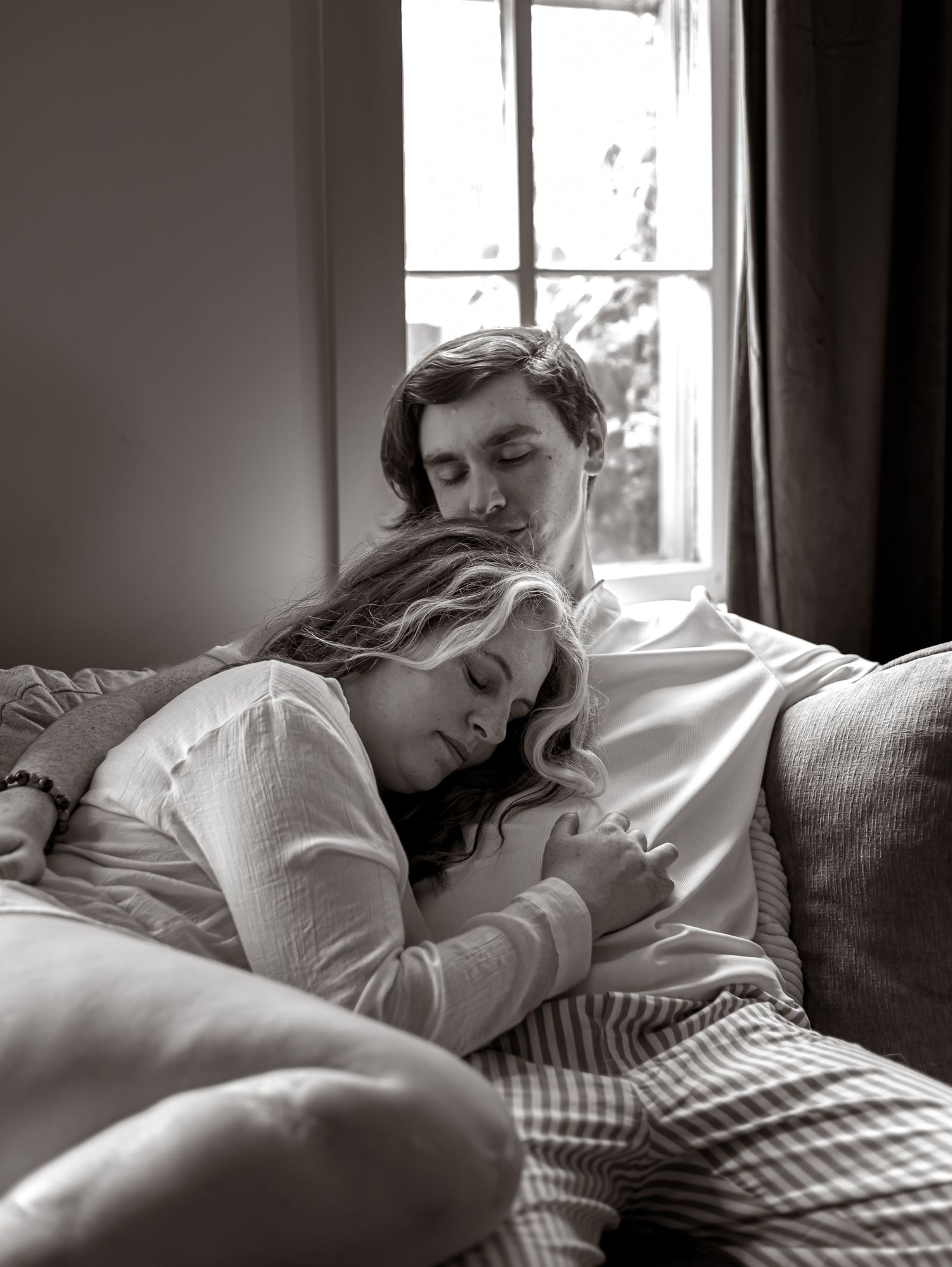 Black and white photos of someone resting peacefully on a couch near a window with soft natural light.