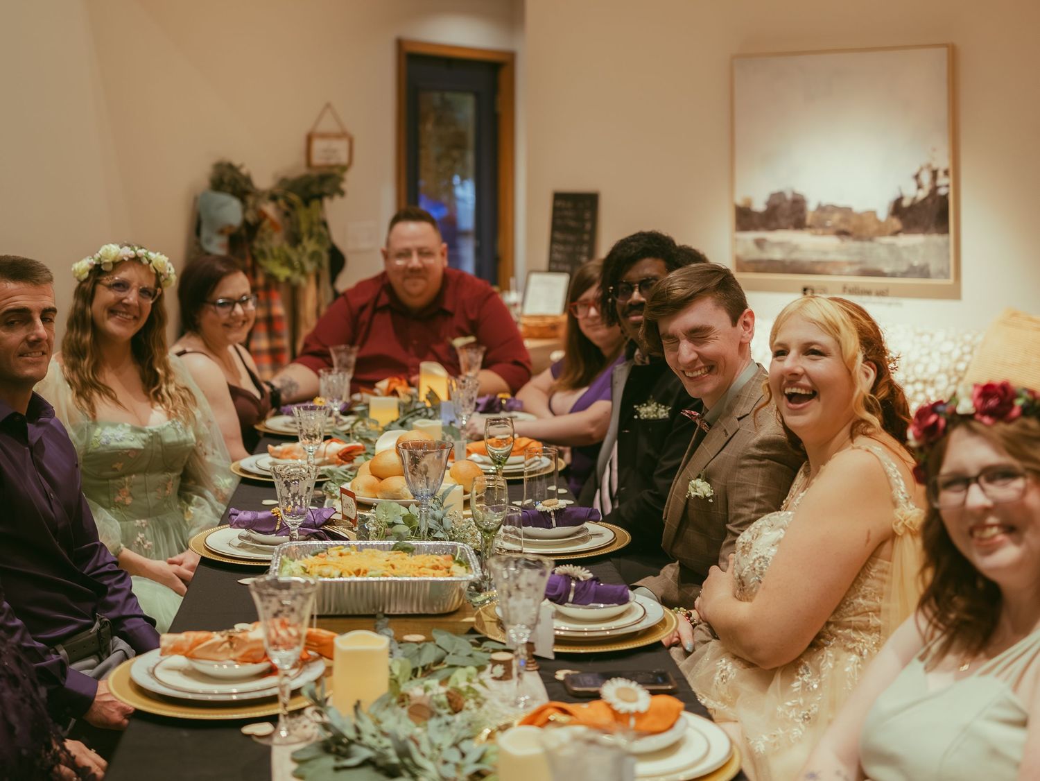 Wedding reception dinner table with guests enjoying a festive meal in an indoor setting.